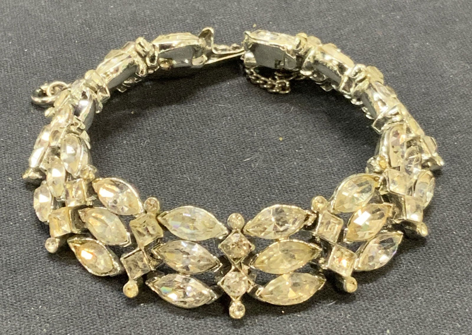 KRAMER Silver Tone Crystal Bracelet: Vintage Kramer silver tone bracelet with crystal decoration. Signed to clasp. Measures approx. 7 inches long. Some surface wear including scratching observed. 1 crystal needs replacement. Estate jewel