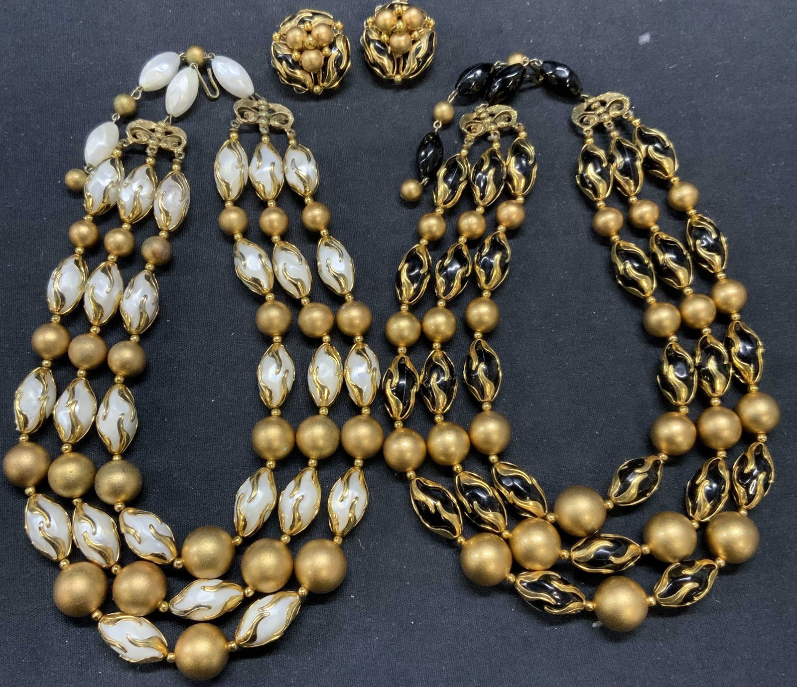 3 DEAUVILLE Gold Tn Necklaces & Earrings: Lot of 3 jewelry pieces. Vintage DEAUVILLE matching black and gold tone and white and gold tone beaded necklaces and 1 pair of black and gold tone clip on earrings. Signed on necklace clasps, earrings