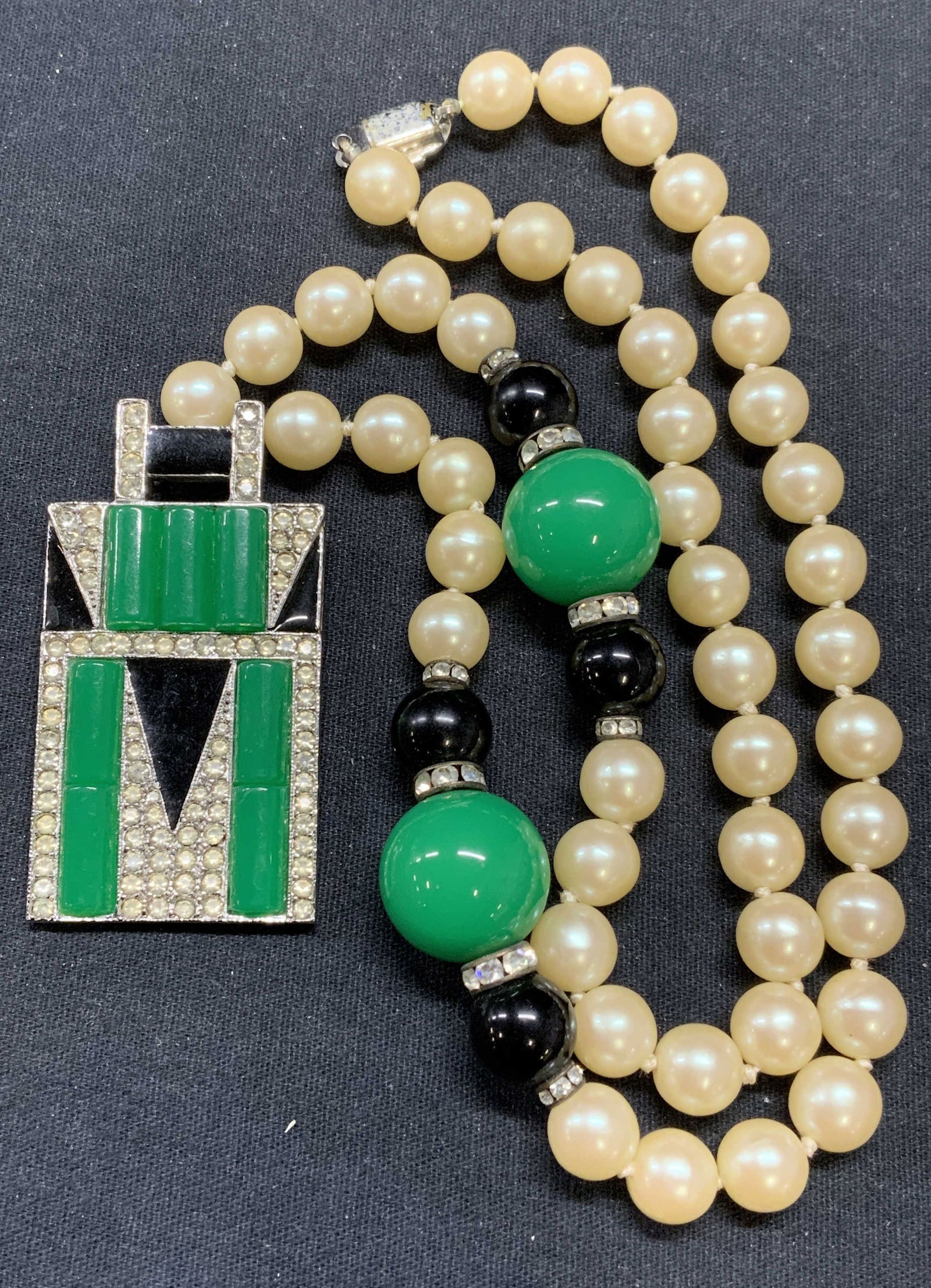 KENNETH LANE Faux Pearl Crystal Pendant Necklace: Vinatge Kenneth Lane KJL faux pearl pendant necklace with crystal decoration, black enamel, and green lucite. Signed to underside of pendant. Drop length approx. 11 inches. Pendant measures approx 2.2