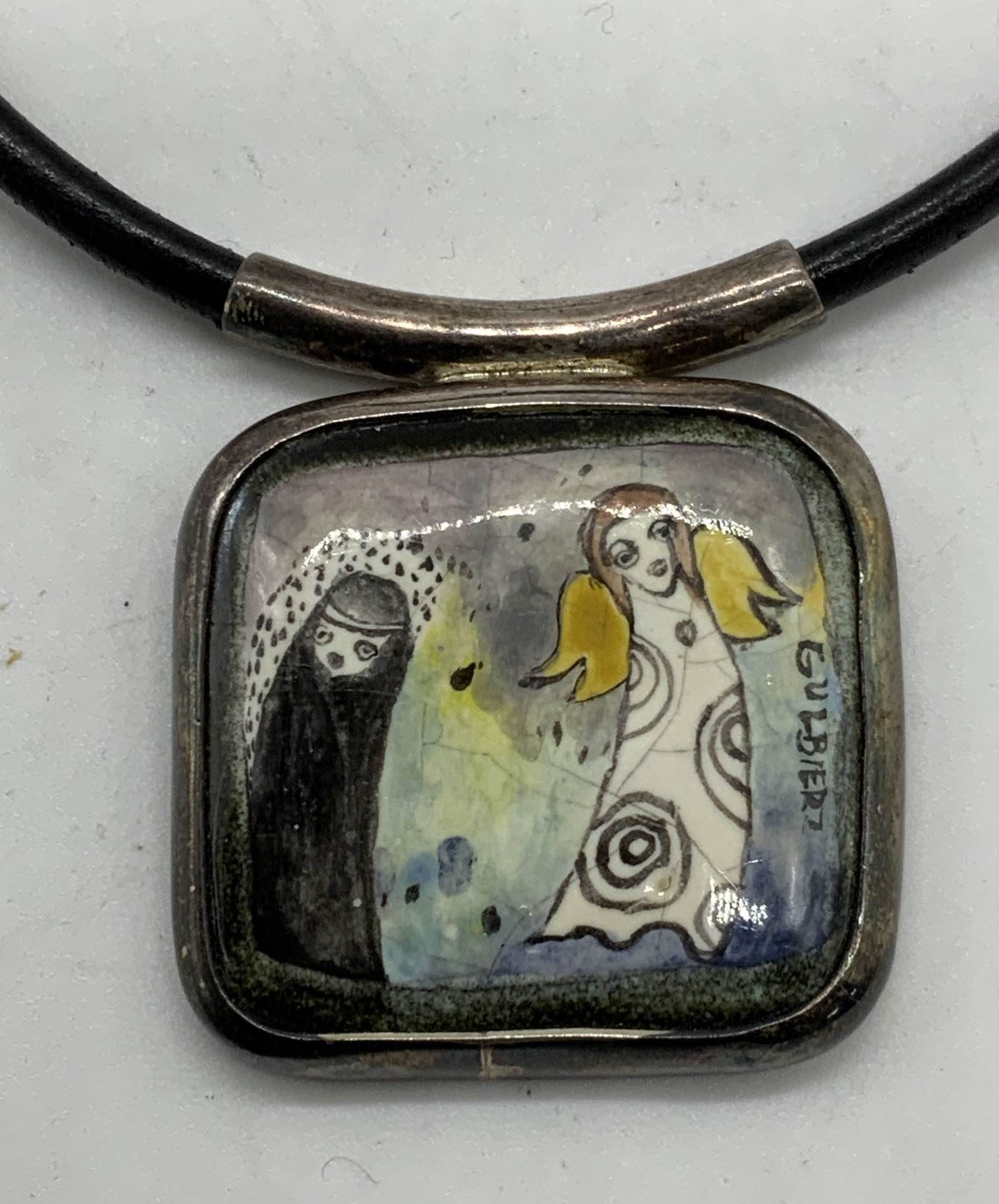 Gulbier Artisan Sterling Silver Pendant Necklace: Signed artisan necklace with sterling silver covered enameled pendant with figural motif on leather cord. Signed on pendant, reads Gulbier. Drop length approx. 6 inches. Pendant measures approx. 1 3/8