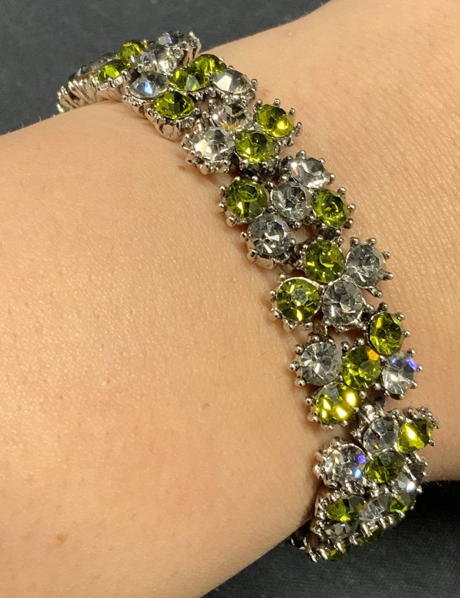 TRIFARI Green & Colorless Crystal Bracelet: Vintage Trifari silver tone green and colorless crystal decorated bracelet. Signed on clasp. Measures approx. 7 inches long. Some surface wear including scratching observed. One crystal needs replacem