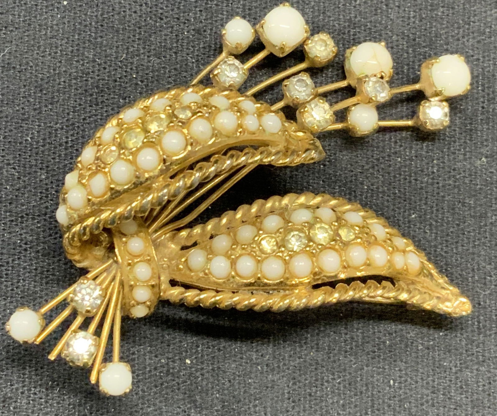 HATTIE CARNEGIE Gold Tone Crystal Flower Brooch: Vintage Hattie Carnegie gold tone crystal and white Cabochon decorated flower brooch. Signed to underside. Hinge pin to underside. Measures approx. 1.5 x 2.25 inches. Some scratching observed. Hattie