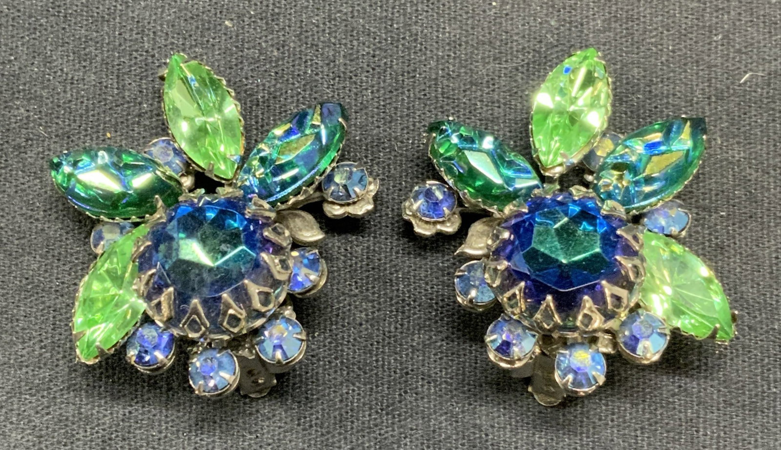 JUDY LEE Blue & Green Crystal Flower Earrings: Vintage Judy Lee silver tone blue and green crystal decorate flower clip on earrings. Signed to underside. Measure approx. 1.5 x 1.25 inches. Some scratching observed. Estate jewelry, costume jewelry,