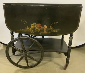 Atq Asian Chinoiserie Drop Leaf Lacquered Tea Cart: Tea cart is antique. Piece is black toned lacquered wood. Tea cart has 2 spoked wheels. Piece has hand painted figural detail dressed in traditional Asian clothing with landscape in background. Tea ca