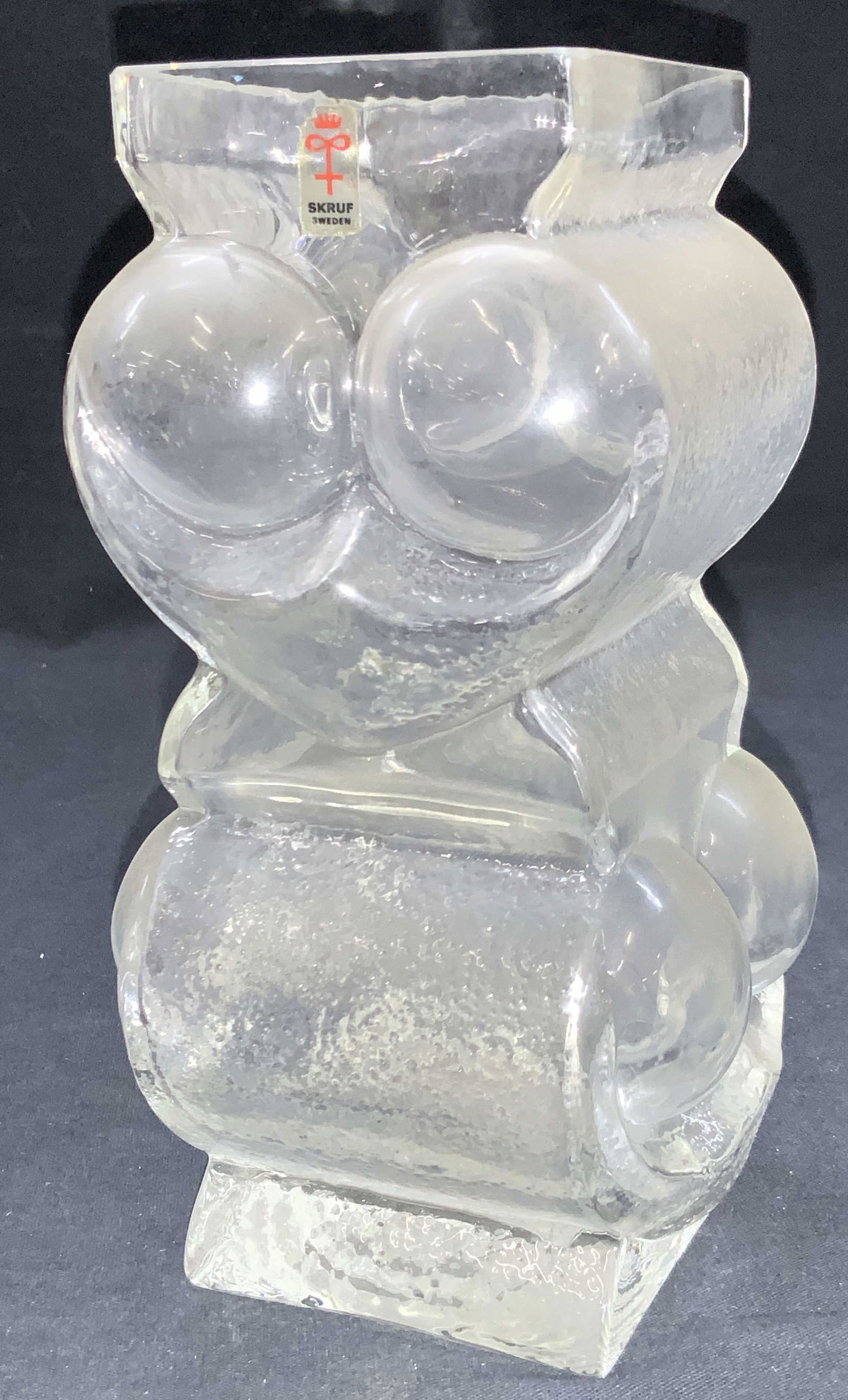 Lars Hellsten For Skruf Swedish Owl Glass Vase: Marked on sticker on top rim reads Skruf Sweden. Clear glass vase with motifs of an owls face throughout. Approx 7.75 inches tall and 3 x 3 inch diameter. Moderate surface wearing due to age and use.