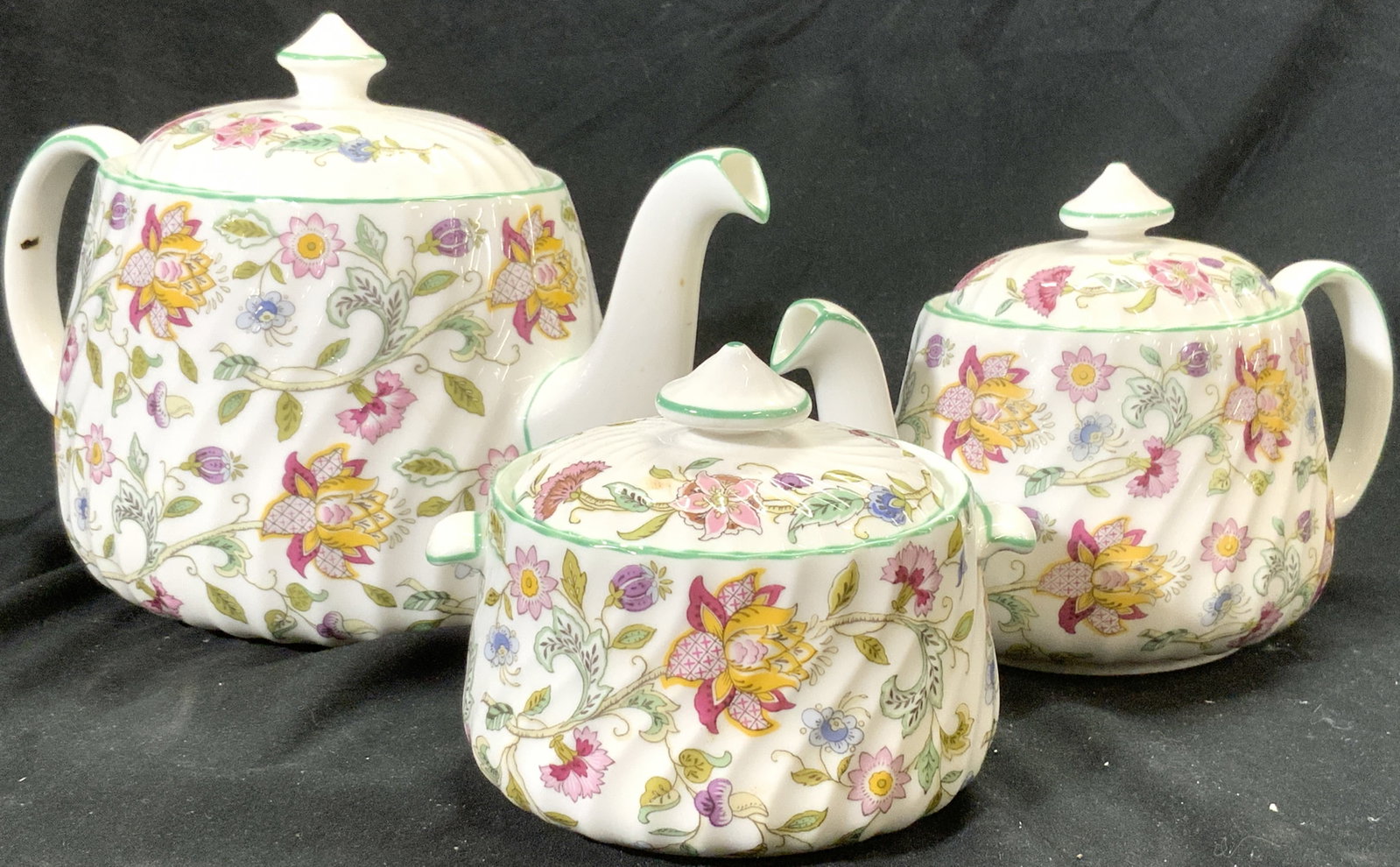 3 MINTON Lidded Porc Teapot, Creamer & Sugar Dish: Lot includes 1 teapot, 1 creamer dish , and 1 sugar dish. Each piece is porcelain & has intricate floral and leaf detail. All dishes include lids. Teapot measures approx 9.5 inches deep 6 inches tall 