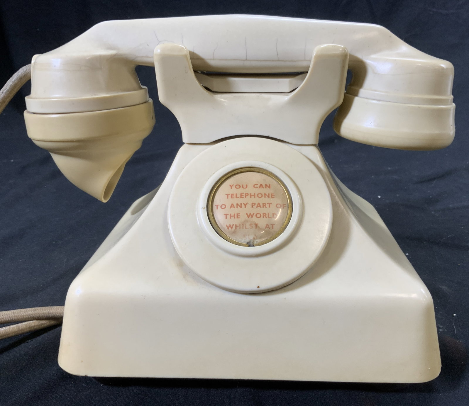 GEC Vintage Corded Telephone ENGLAND: Backside reads GEC. Piece also reads MADE IN ENGLAND. Telephone is vintage. Piece is cream toned. Center has button which reads YOU CAN TELEPHONE TO ANY PART OF THE WORLD WHILST AT SEA. Telephone is c