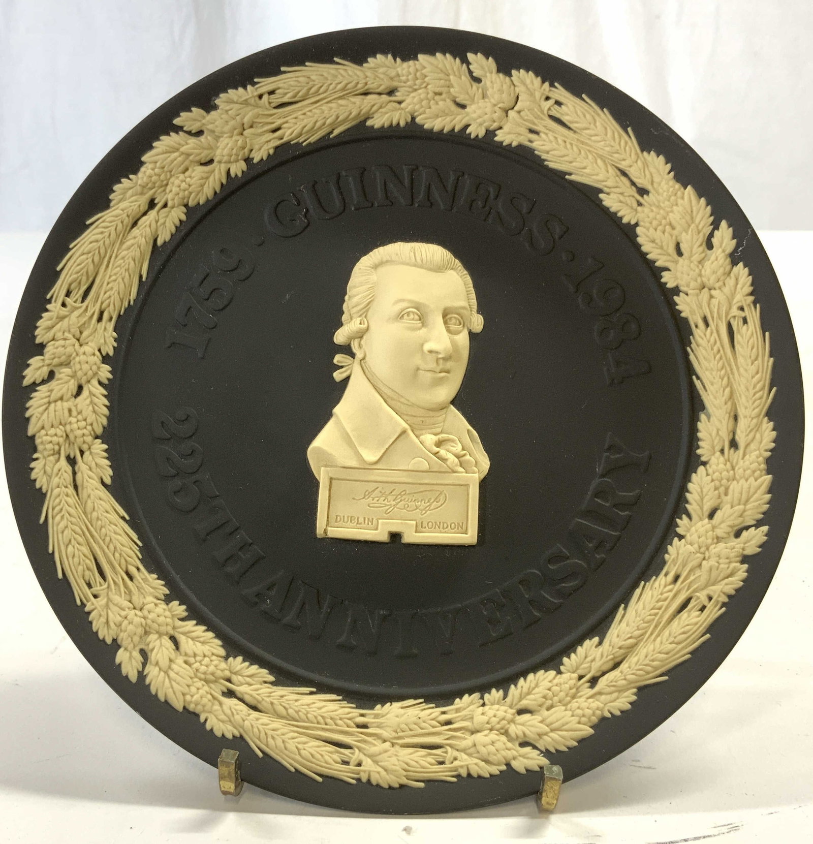 WEDGWOOD GUINNESS 225th Anniversary Plate 1984: Underside is inscribed WEDGWOOD ENGLAND. Plate is vintage circa 1984. Piece is black toned with cream toned depiction of founder ARTHUR GUINNESS, leaf & barley detail near rim. Plate reads 225th ANNIV