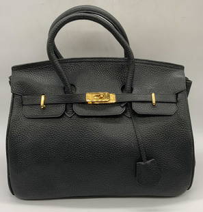 HERMES Black Leather Birkin Bag France: A black leather Hermes Birkin Bag. Twist lock gold tone metal closure and gold tone metal hardware that reads HERMES. Two top handles. Four gold tone metal feet. Cloche contains key. Interior and exte