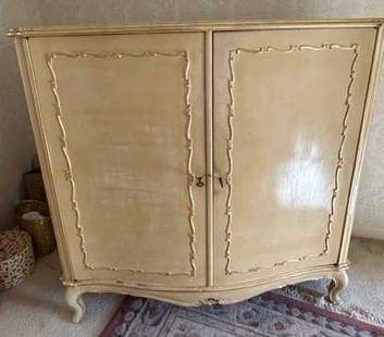 Vintage Austrian Carved Two Door Armoire: Vintage possibly antique hues with raised gilt wood accents to the obverse. Floral designs along the top. Two doors open to reveal custom drawers. Two keys to interior. Curled legs. Measures approx. 6