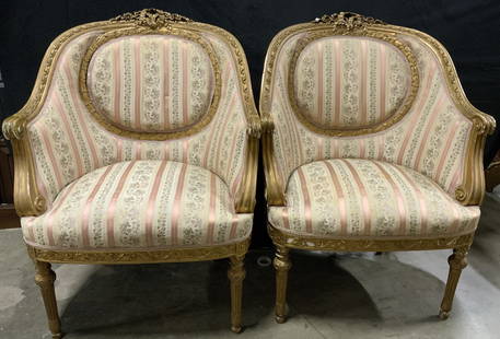 Pair Antique French Gilt Louis XVI Armchairs: A pair of antique armchairs. Carved gilt wood throughout. Floral and foliage motifs throughout. Scrolled arms. Soft hand upholstery features stripes, florals, and foliage. Pink, beige, blue, green, an