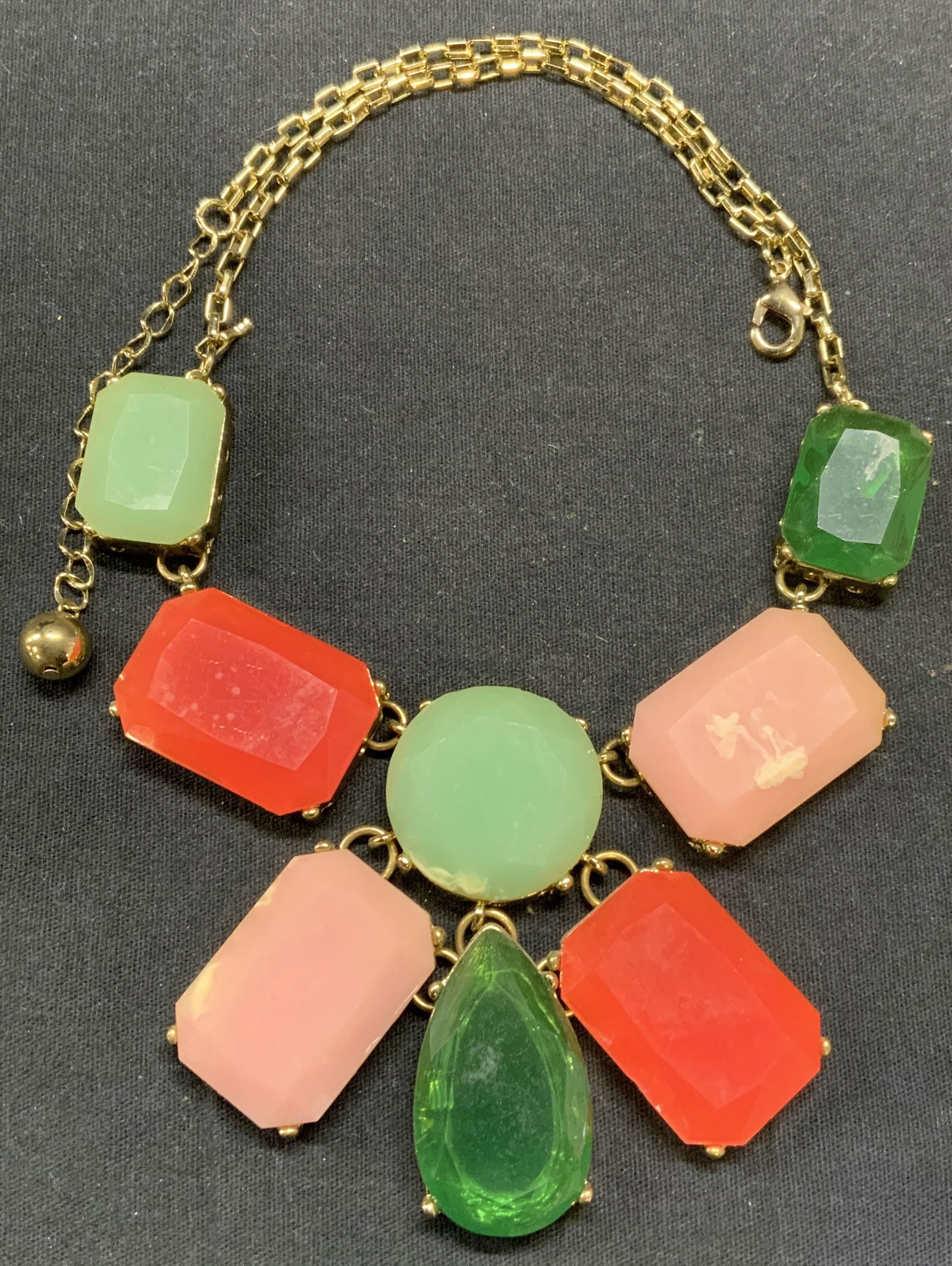 Gold Tone Pink & Green Crystal Pendant Necklace: Gold tone pendant necklace with pink and green crystal decoration. Drop length approx. 9 inches. Pendant drop approx. 3 inches. Some scratching observed. Property of Manhattan estates and fashion indu