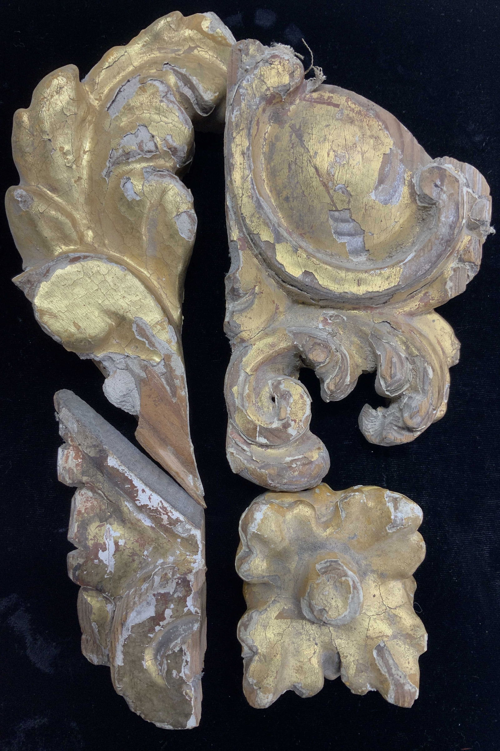 Antique Gilt Wood Wall Ornaments, 4: Hand carved wood pieces, possibly remnants from a frame, neoclassical style pieces with scrolling, heavy gold leafing. Areas of interior mortar . Larger pieces measure 7.5 x 3 in. and 6.5 x 4 in. Scre