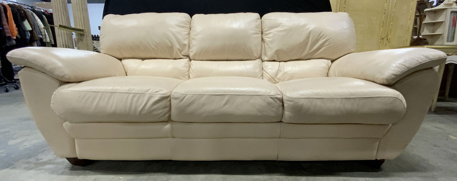 Neutral Tone Leather Sofa: A neutral tone leather sofa. Three seat. Measures approx. 37H x 34.5D x 83W in. Cushions do not appear to be removable. Four wooden feet. Some discoloration and surface wear present. Seating, couch, s