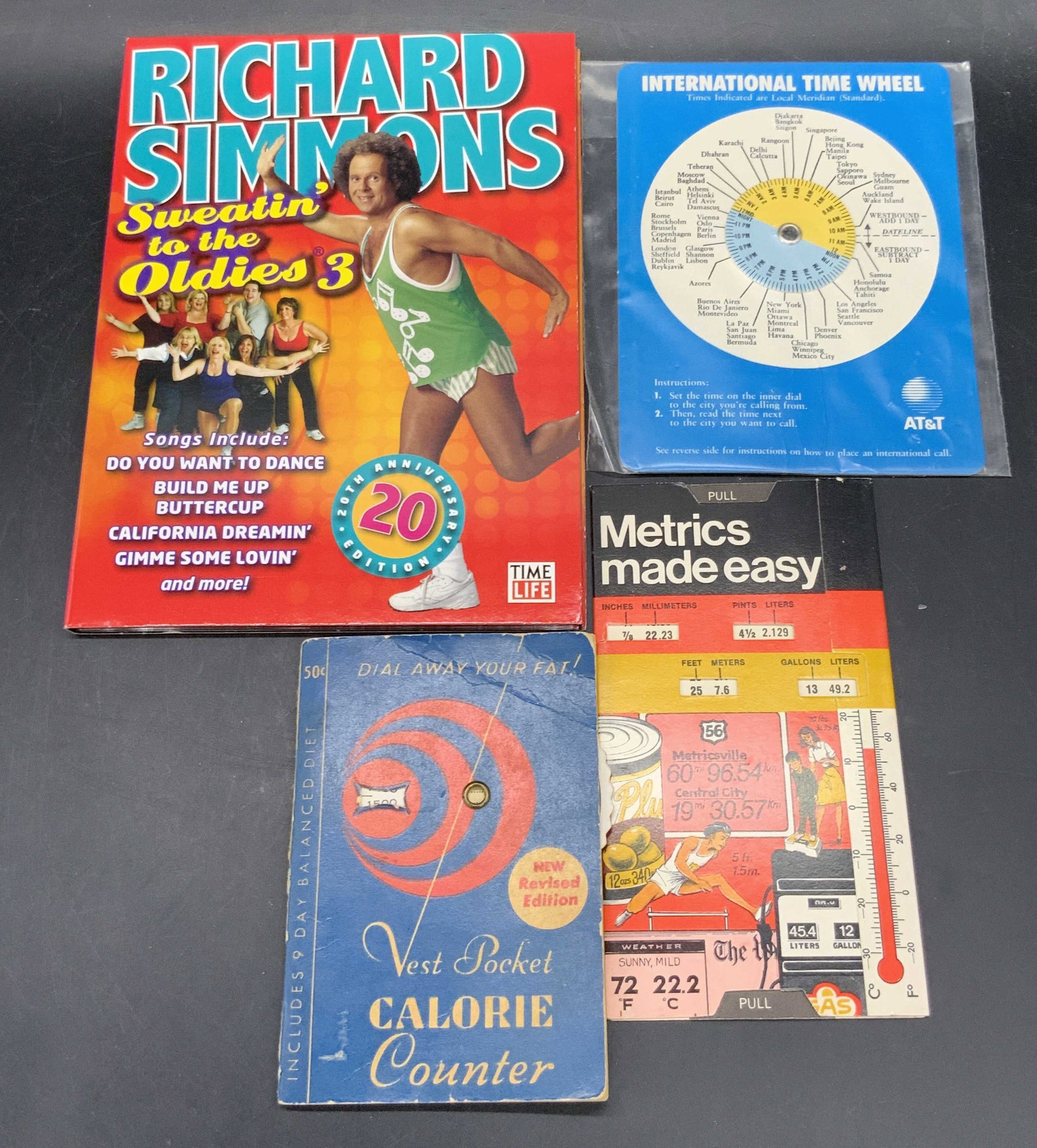 4 Vntg Ephemera & Richard Simmons DVD, 1961 &1986: A lot consisting of a Richard Simmons Sweatin To The Oldies 3 DVD, Metrics Made Easy ephemera, 1961 Dial Away Your Fat Vest Pocket Calorie Counter pamphlet, and a 1986 International Time Wheel. Larges