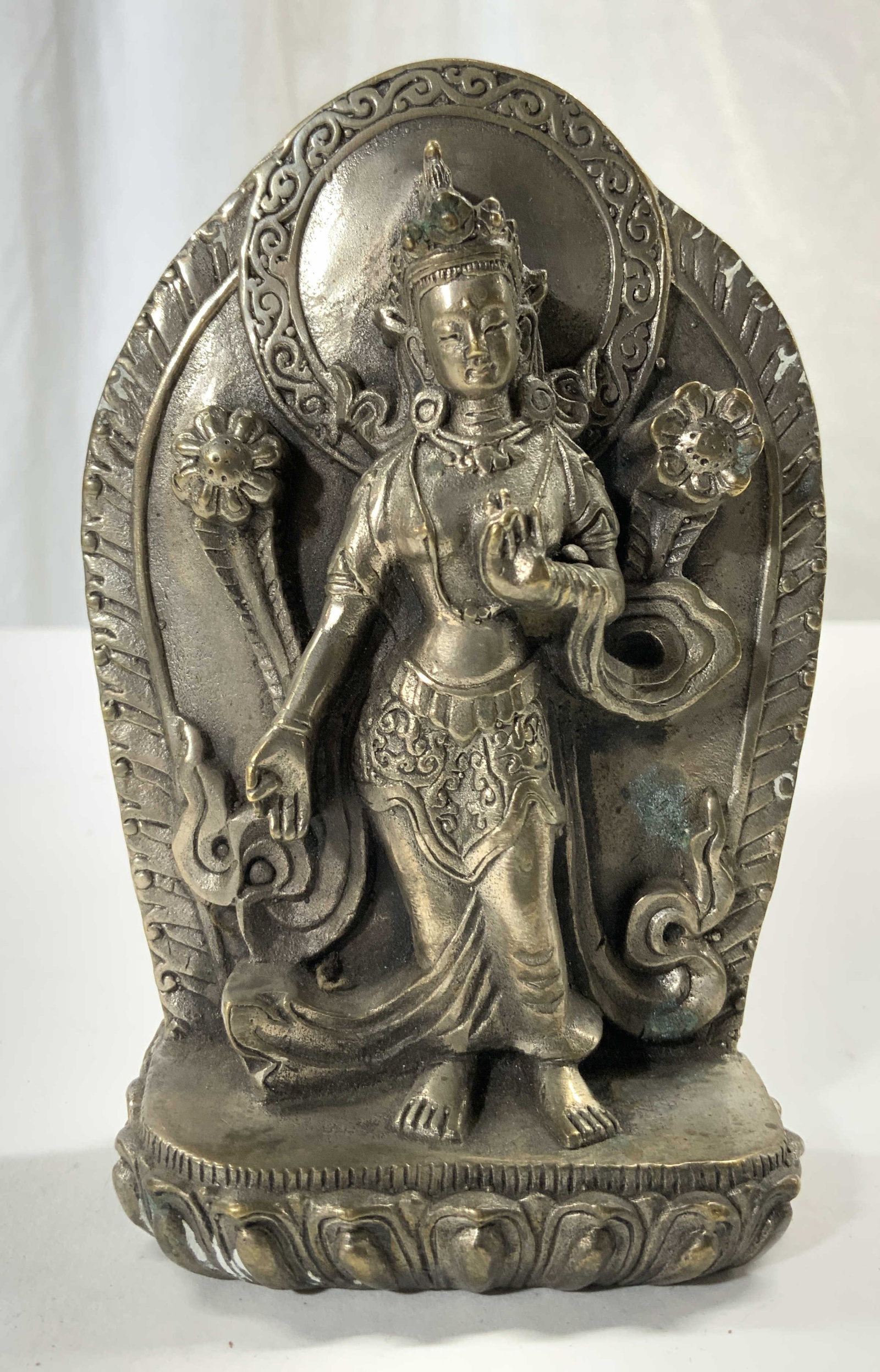 Vtg Silvered Brass Buddhist Diety Sculpture Figure: Figure appears to be silvered brass. Piece depicts Buddhist diety figure with hand in Vitarka position. Standing next to flowers 5 inches tall 3.5 inches wide 1.25 inches deep. Buddhist diety, Buddhis