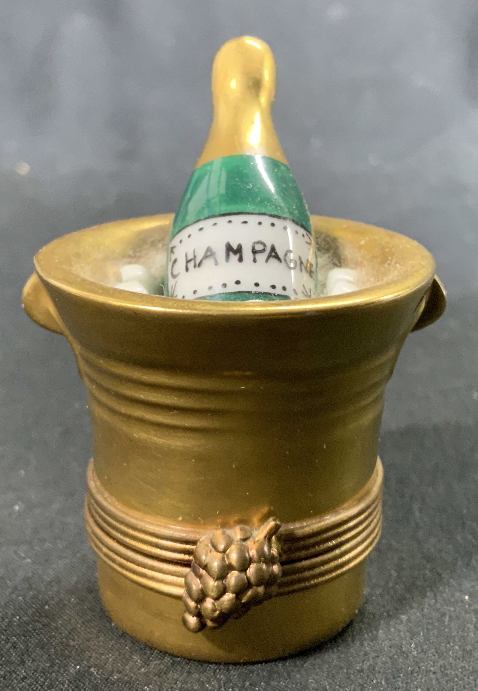 LIMOGES FRANCE MARQUE DEPOSE Ice Bucket Pill Box: Underside reads LIMOGES FRANCE MARQUE DEPOSE PEINT MEIN. Trinket box is porcelain with gilt detail. Piece has shape of champagne bucket with bottle inside. Measures approx 2.25 inches tall 1.75 inches
