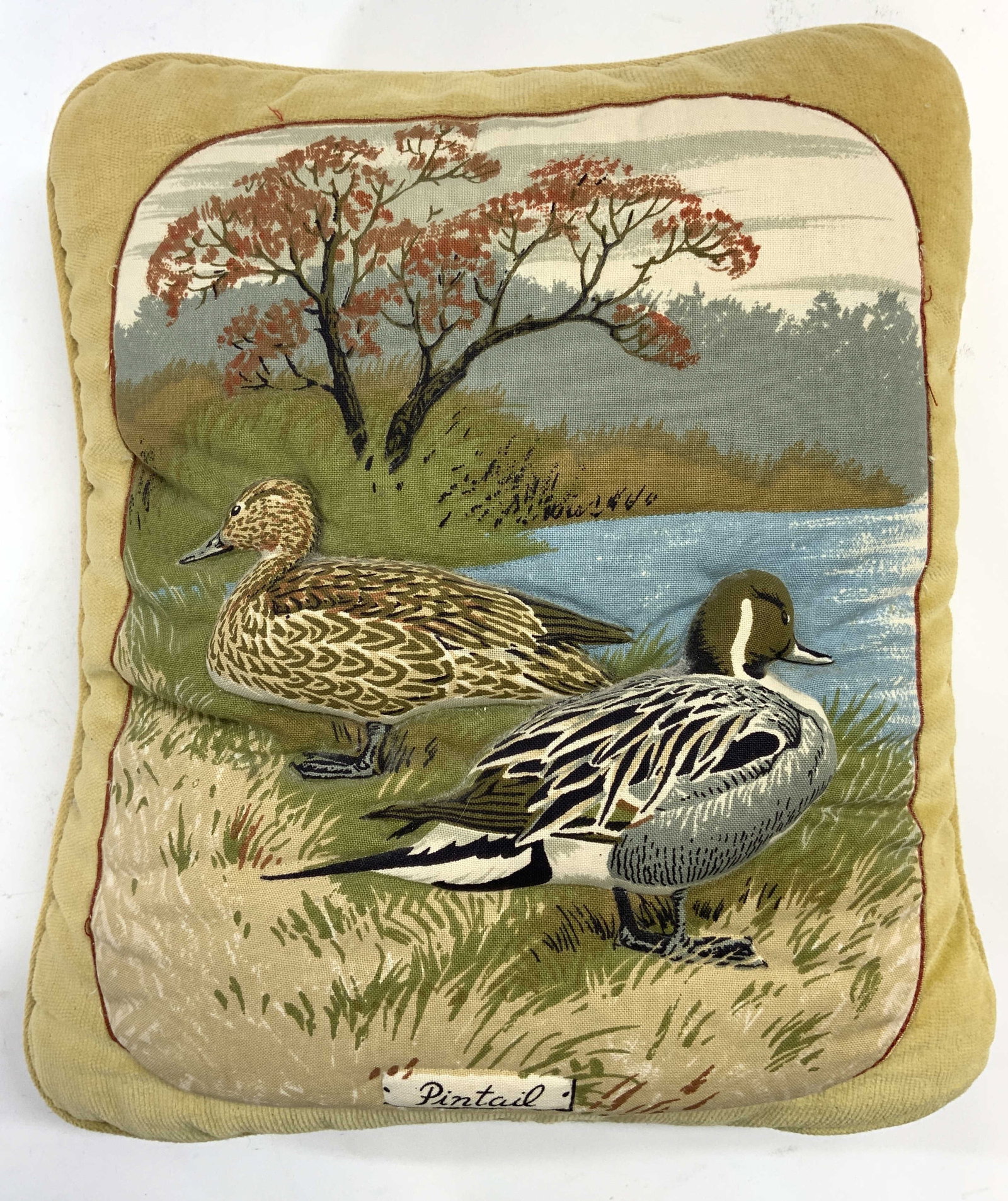 Mid Century Pillow Quilted Pintail Duck Detail: Pillow is vintage. Piece is embroidered with beveled pintail duck detail within lakeside scenery landscape. Pillow has saffron yellow tone. Base of image reads PINTAIL. Piece measures approximately 15
