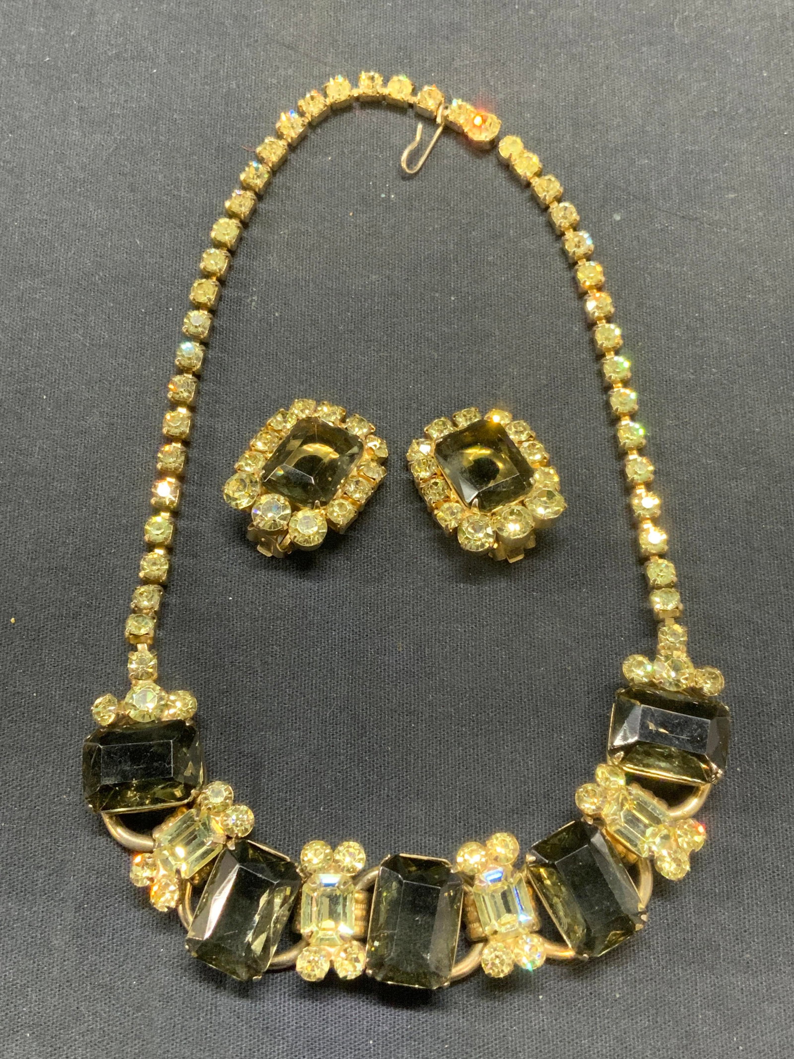 Lot 2 Matching Smokey Crystal Necklace & Earrings: Lot of 2 jewelry. Vintage matching gold tone crystal necklace and clip on earrings with Smokey gray and pale yellow crystal decoration. Necklace drop length approx. 6.5 inches. Earrings measure approx
