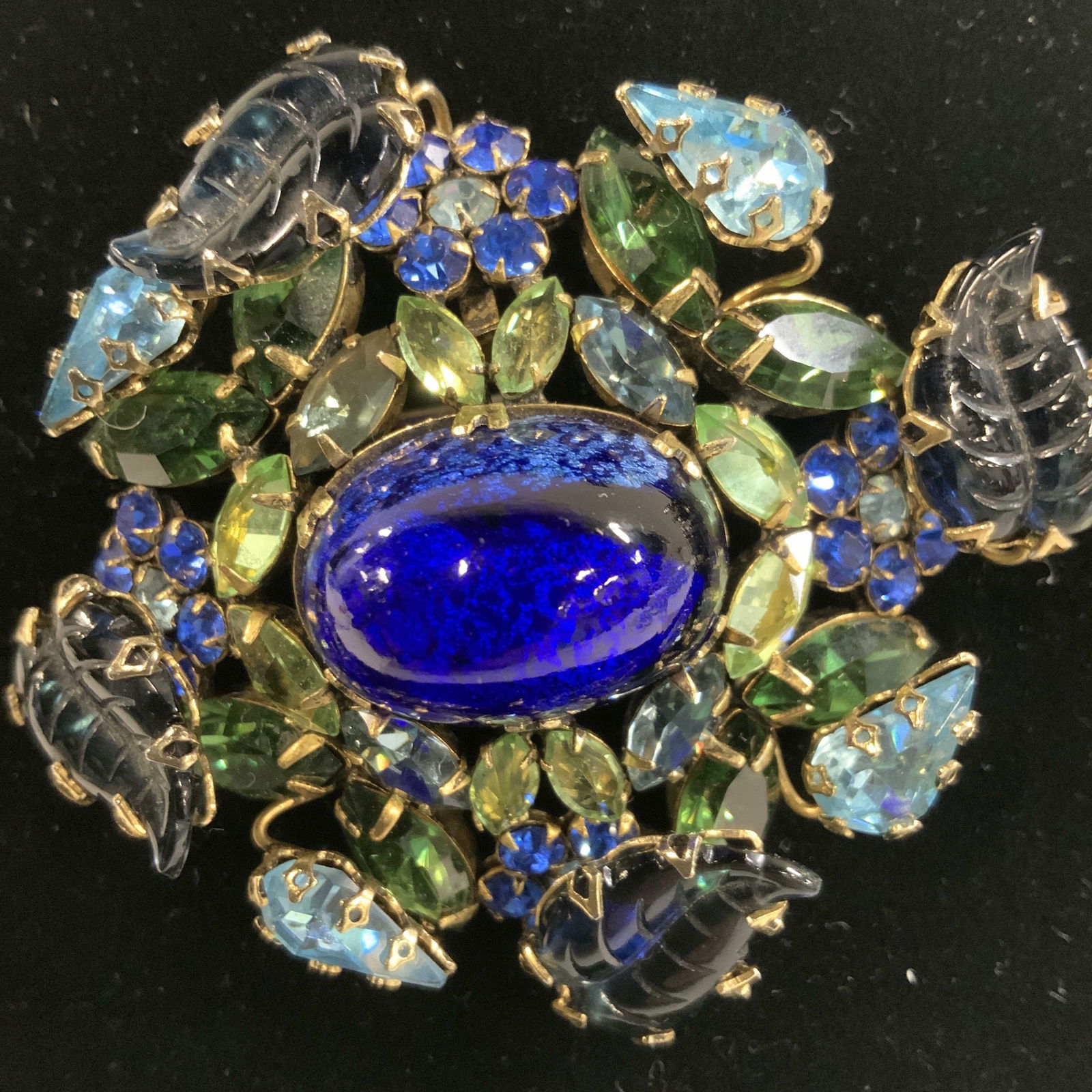 SCHREINER Bejeweled Art Nouveau Glass Brooch: Statement Schreiner Brooch with a larger center cobalt glass oval cabochon with silver metallic flakes. Cabochon is surrounded by green Marquis crystals, cobalt blue crystal flowers and etched blue gl