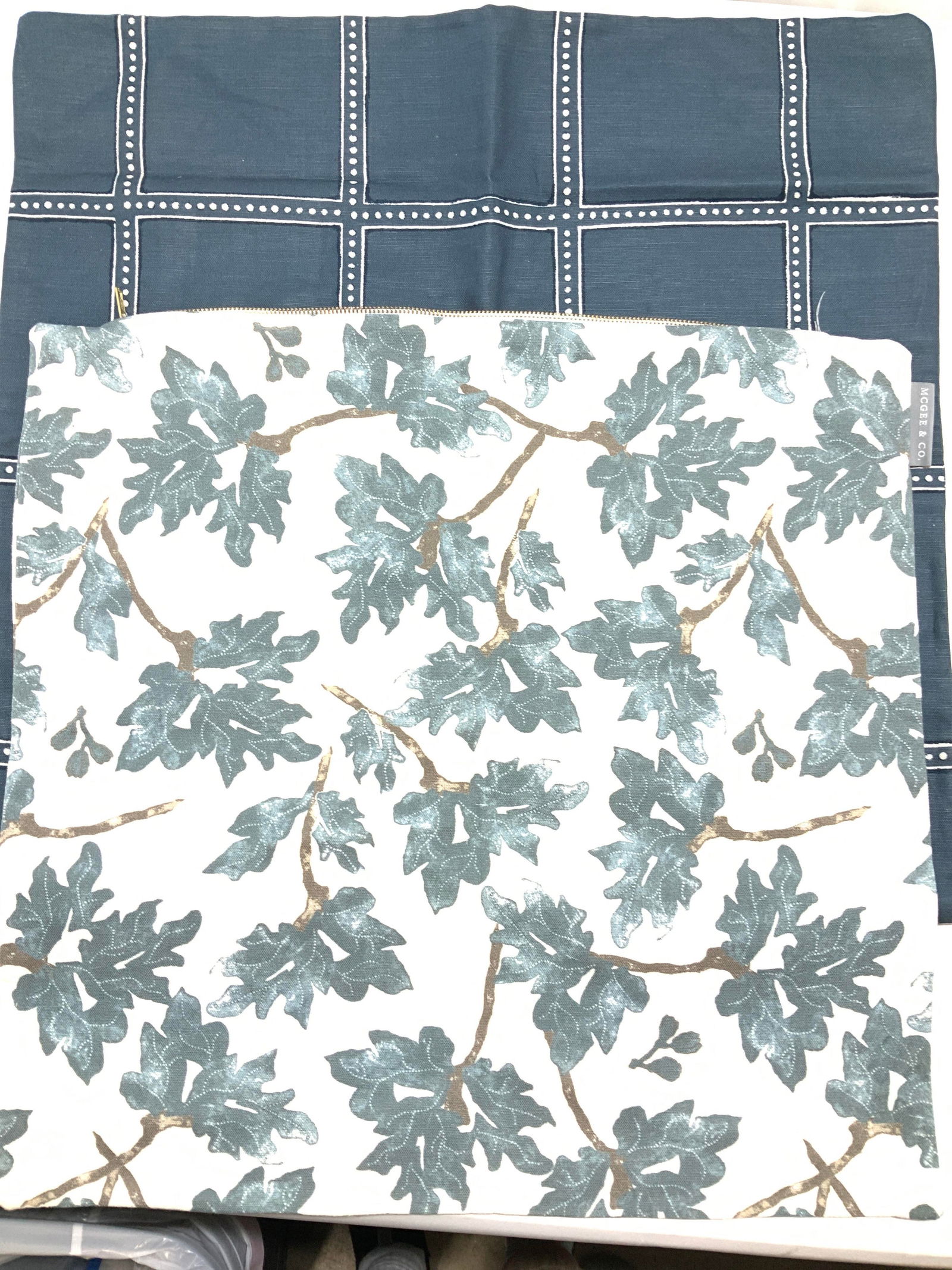 McGee & Co Zippered Linen Pillow Covers: Signed McGee & Co thick linen pillow covers. One cream with grey- blue tree branch leaves, the other a charcoal blue and polka dot square pattern. Leaf pillow case measures 20 in. Other measures 22 x
