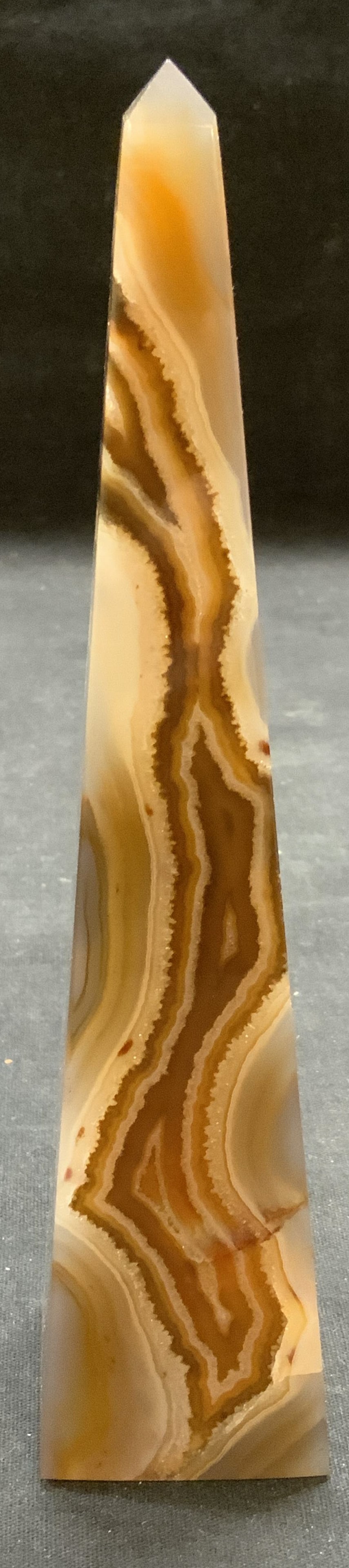 Tan Banded Agate Obelisk Tower: Tan toned banded agate obelisk tower. Measures approx. 1.75 x 1.75 x 7.5 inches. Piece has weight. Some scratching observed. Agate obelisk, agate tower, crystal obelisk, crystal tower, collectibles, h
