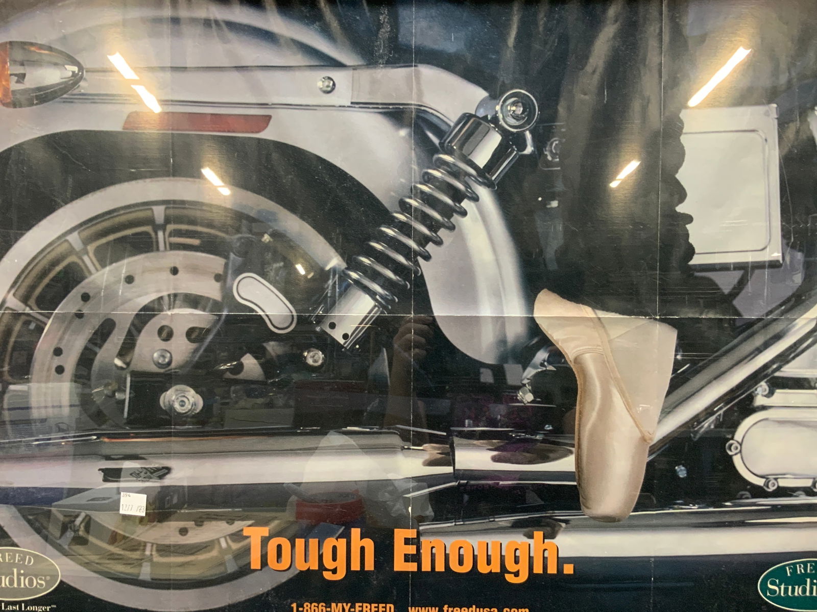 Harley Davidson Tough Enough Advert Litho: Marked in upper left corner Hardley Davison Motorcycles and dance Magazine. Reads Tough enough and shows a ballerina in her shoes and leg warmers next to a motorcycle. Framed in a black plastic frame.