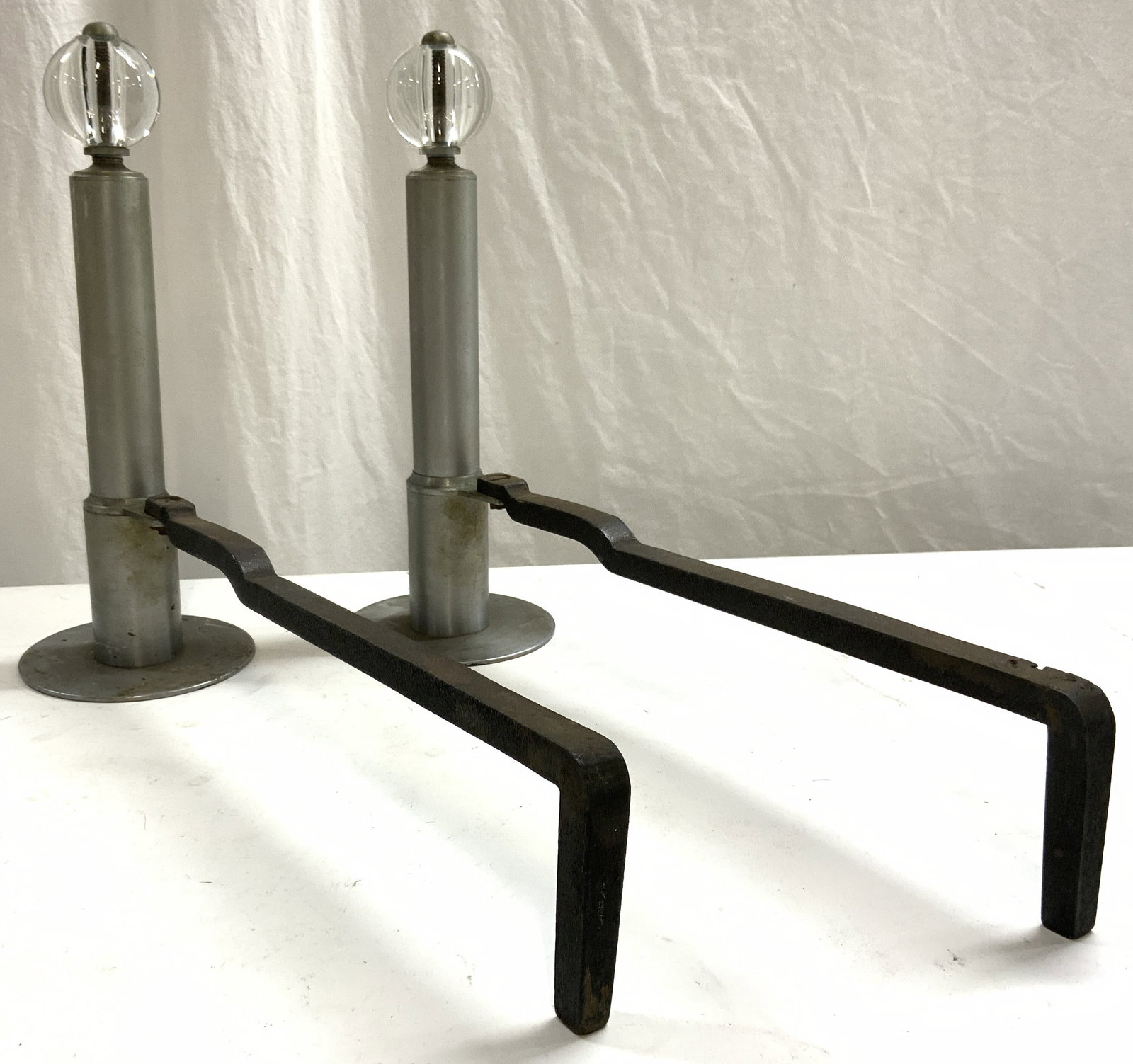 Pr Vintage Iron & Glass Andirons: Lot includes 2 andirons. Each are vintage. Andirons are each iron & metal with glass spherical shaped structures at top. Each piece measures approximately 19.5 inches long 14.5 inches tall 5.5 inches 