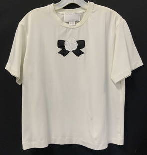 St John Applique White Cotton T Shirt, Italy: This is a St. John White T shirt with a an applique flower and bow in black and white. Zipper along shoulder. Petite medium.23 in. Long. Label reads made in Italy, St. John by Marie gray, St John Spor