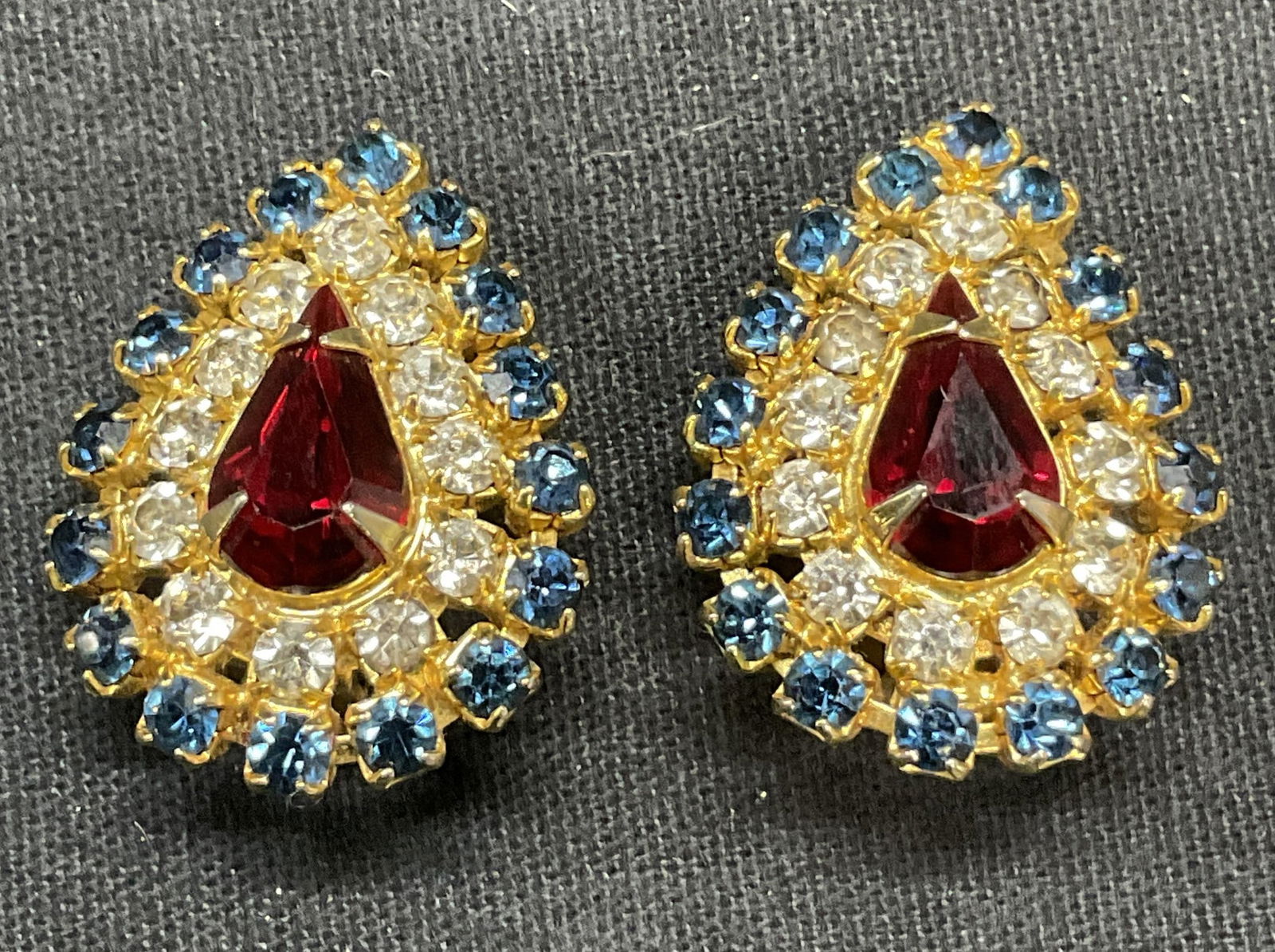 Vintage HOBE Gold Tn Crystal Drop Stud Earrings: Vintage HOBE gold tone drop shaped stud earrings. Red, blue, and colorless crystal decoration. Signed to underside. Clip on backing. Measure approx. 1.25 x 7/8 inches. Some scratching observed. Estate