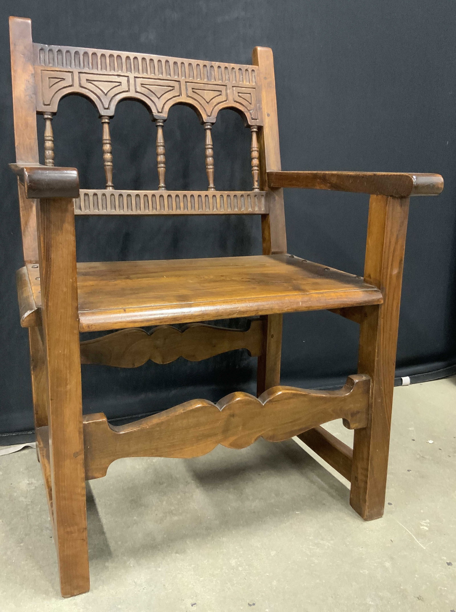 Vintage Handcrafted Wooden Hacienda Chair: Chair is vintage and wooden. Piece has intricately carved detail. Chair has stretchers in between legs. Piece appears to be hand crafted. Arched structures to backrest. Piece measures approx 38.5 inch