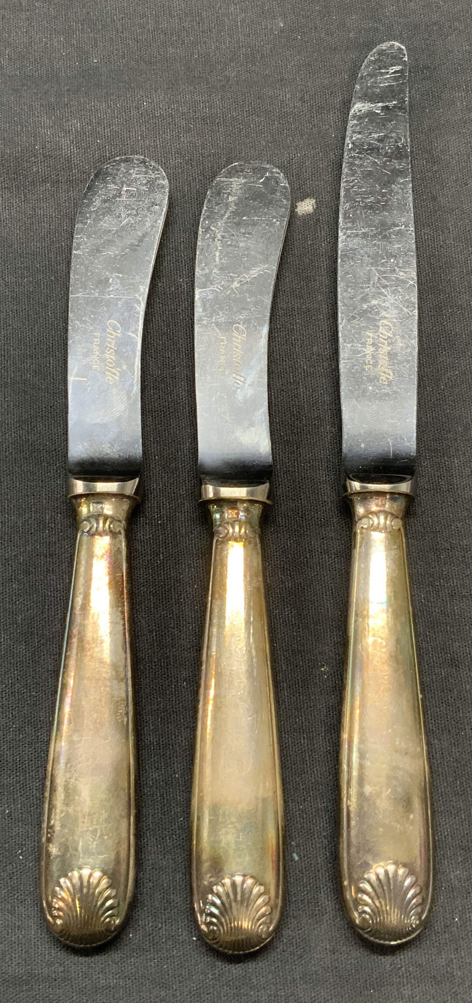 Lot 3 CHRISTOFLE Silver Plated Knives, France: Lot of 3 pieces. CHRISTOFLE silver plated handled butter knife and 2 cheese knives. Embossed shell patterns on handles. Trademarked on blades. Plate quality hallmark on handles. Made in France. Butter