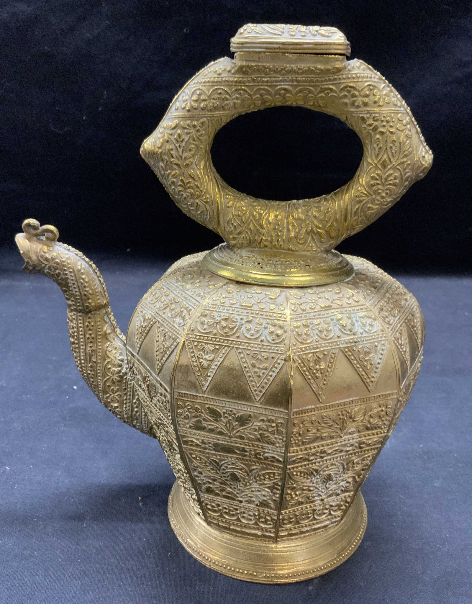 Antique Minagkabau Cast Brass Kendi Kettle: Antique Malaysian Minagkabau cast brass Kendi kettle. Ornate embossed scroll, geometric, and floral motif. Measures approx. 8 x 5.5 x 10 inches. Surface wear including scratching and pitting observed.