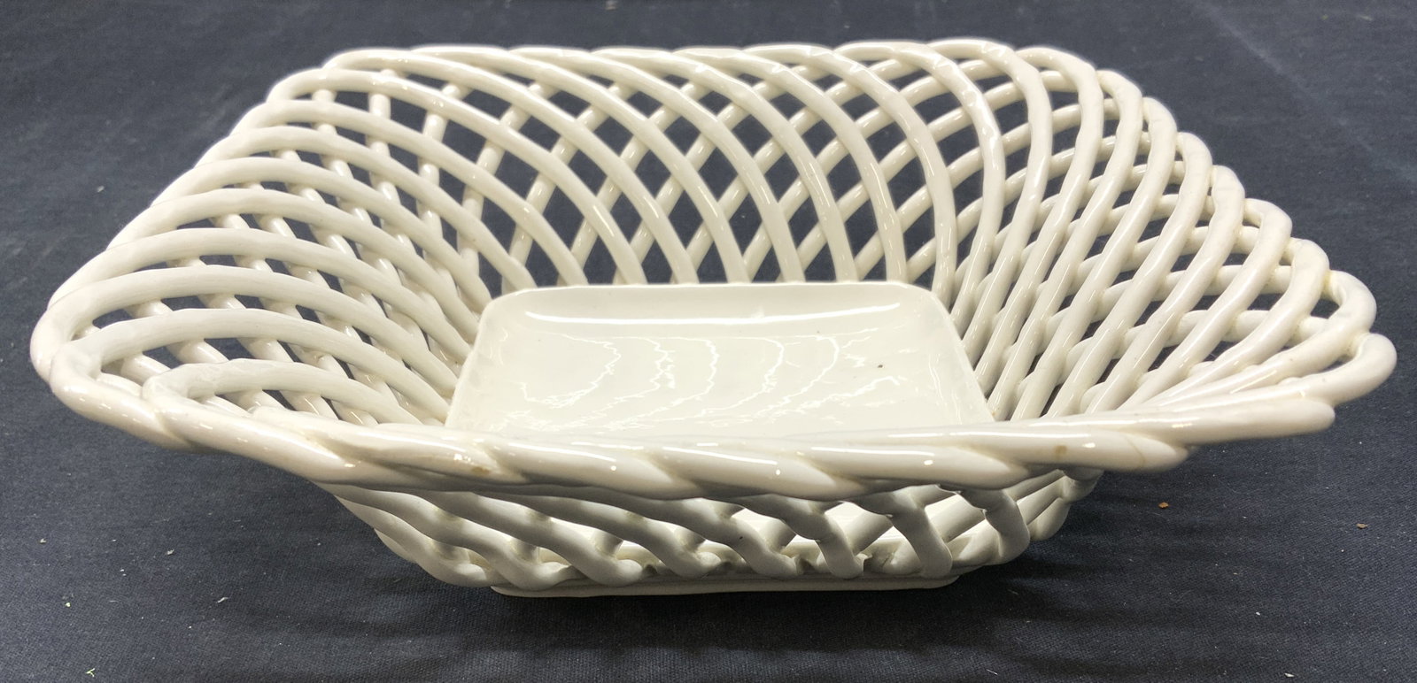 Trademarked Woven Porcelain Bowl Vessel: Underside has shield with flower trademark. Vessel is white toned & porcelain with woven outer area. Piece measures approx 8.5 inches wide & deep, 2.5 inches tall. Bowl, basket, vessel, porcelain vess