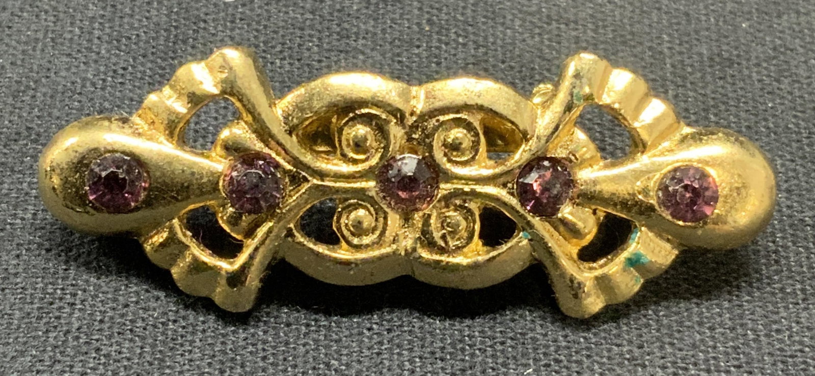 Vintage Gold Tone Purple Crystal Brooch: Vintage gold tone brooch with purple crystal decoration. Art deco style. Measures approx. 1.75 x .75 inches. Some scratching observed. Property of Greenwich Connecticut estate. Owners had relocated fr
