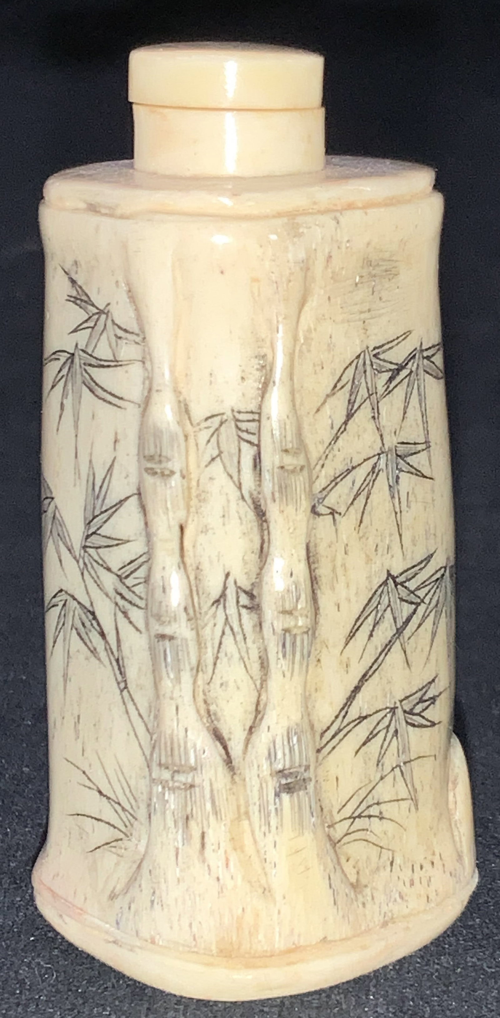 Vtg Carved Bone Asian Snuff Bottle: Vintage Asian snuff bottle, possibly carved from bone with etchings of bamboo on the exterior sides and snuff spoon affixed to cap on top. Approx 2.5 inches tall. Moderate surface wearing due to age a