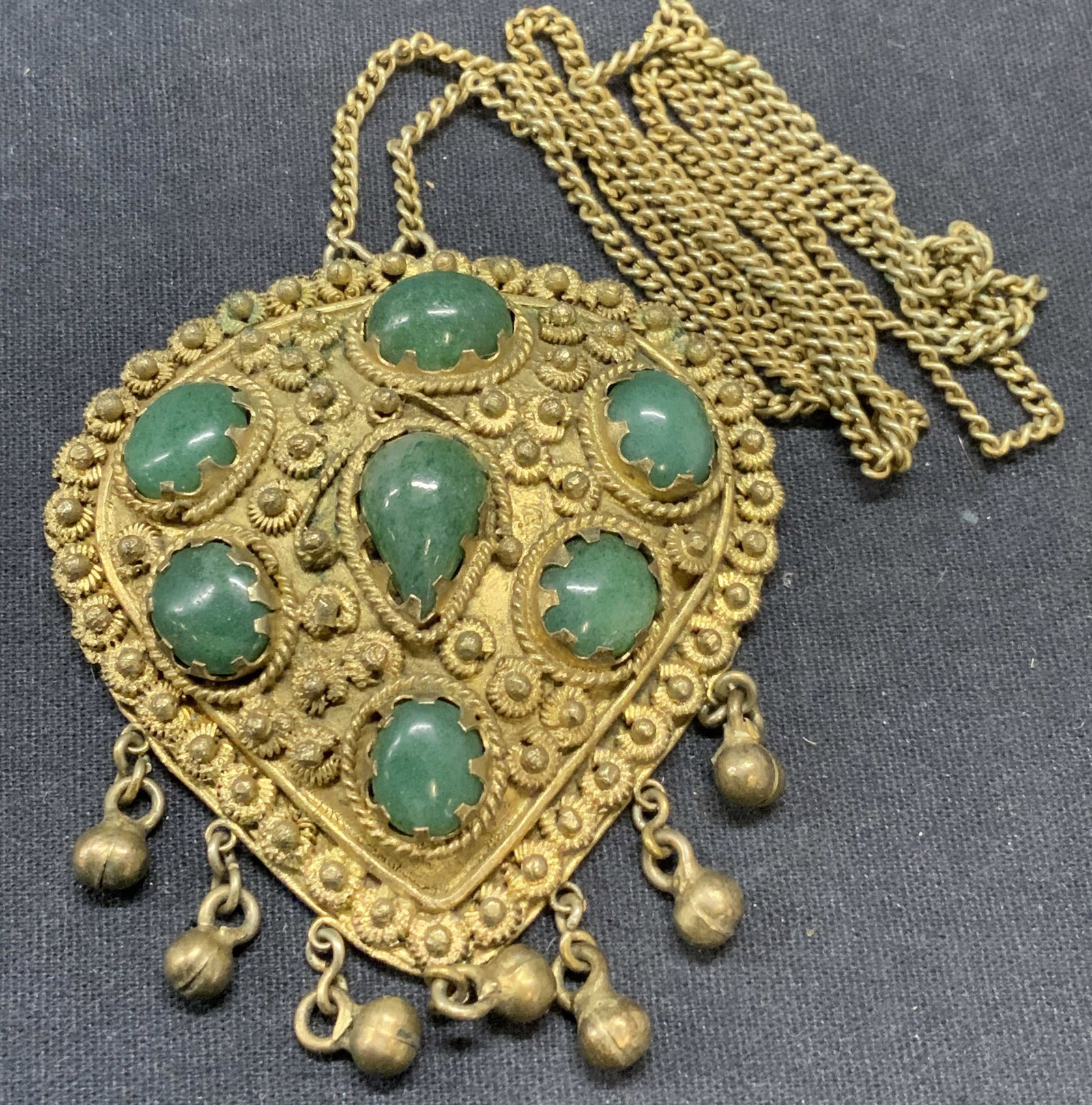 Vintage Gold Tn Green Gemstone Pendant Necklace: Vintage gold tone, possibly plated, pendant necklace with green gemstone decoration. Stones are possibly jadeite. Drop length approx. 13.5 inches. Pendant measures approx. 2.5 x 2.5 inches. Some scrat