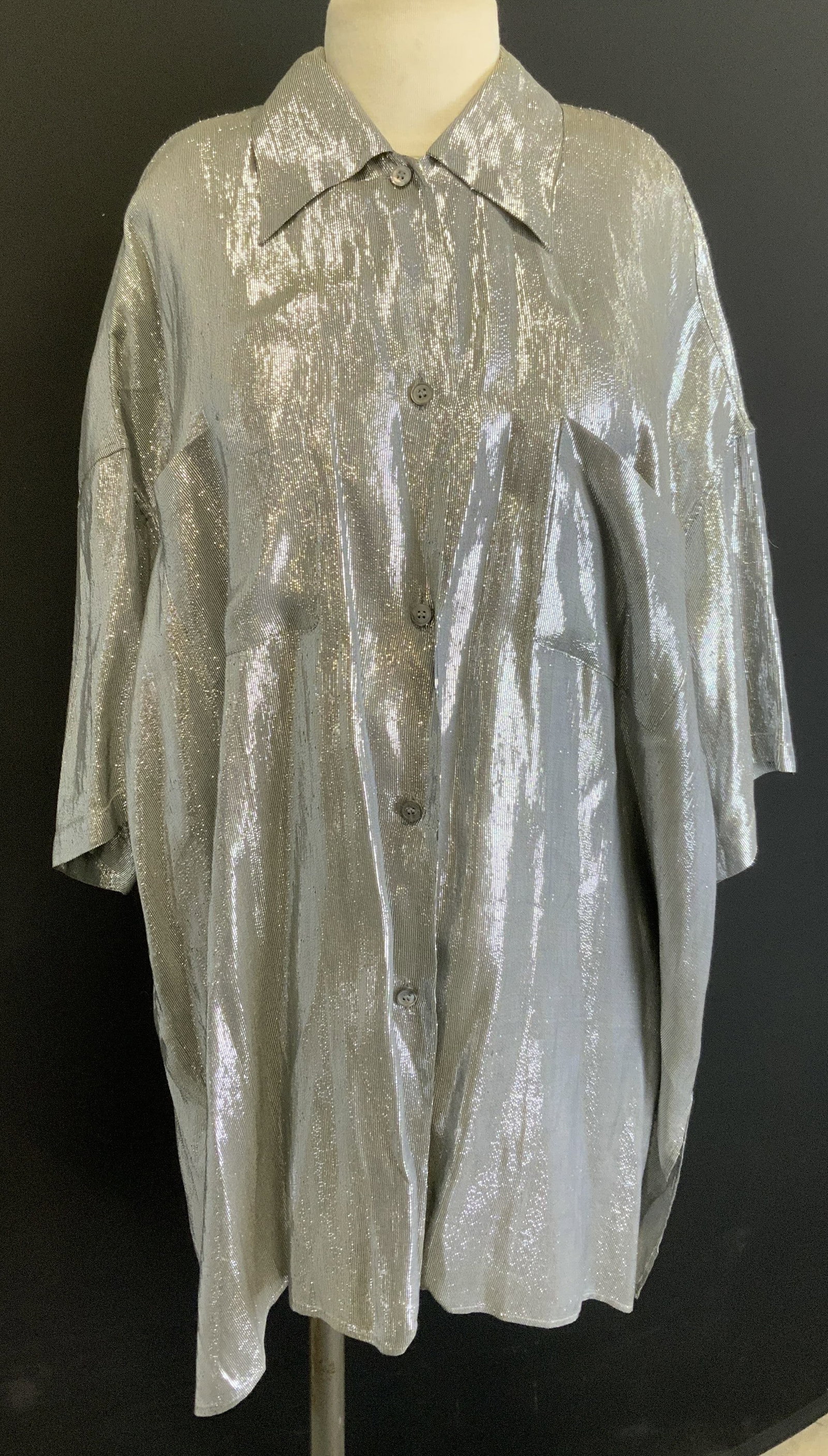 Callaghan Metallic Silver Button Up Top, Italy: Callaghan metallic silver short sleeve button up top. Size 46. Made in Italy. Synthetic and silk blend. Previous repairs and tearing to fabric observed. Property of Manhattan estates and fashion indus
