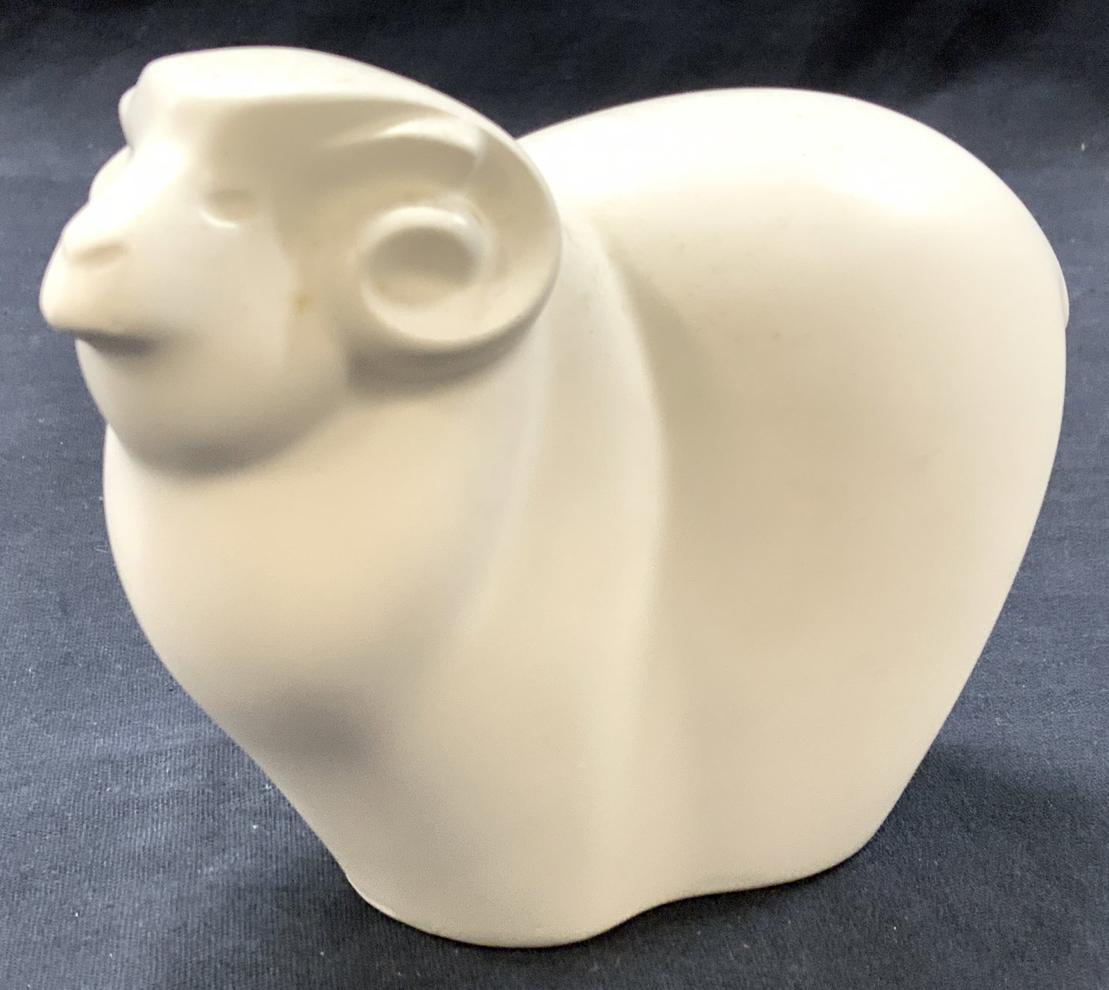 Stamped Plaster Made Ram Figure: White plaster made figure of a ram with minimalist body and curled horns. Stamped on lower half of figure with an R. Approx 4 inches tall and 5.5 inches long. Moderate wearing to white surface Plaster