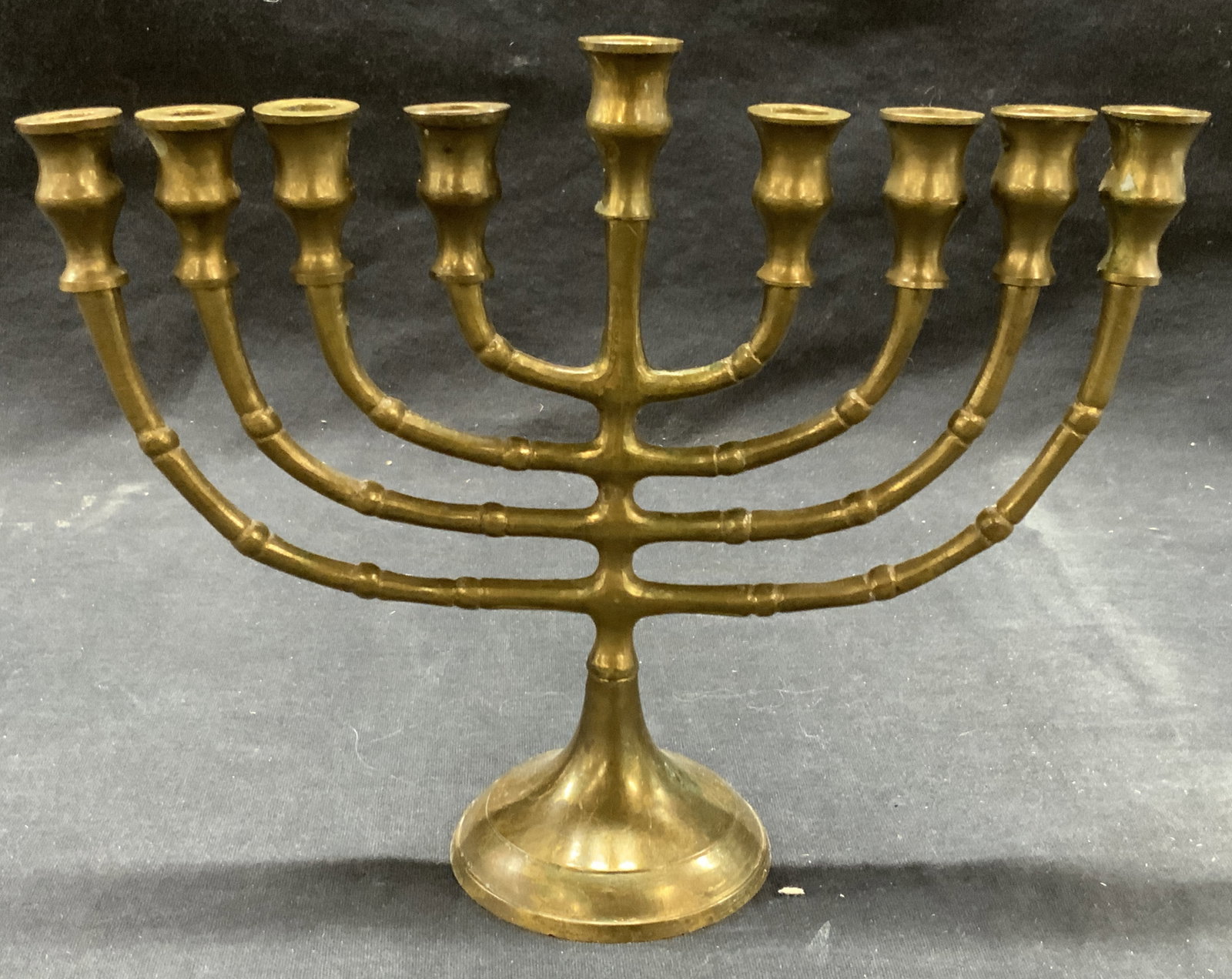 Vintage Brass Made Menorah: Vintage brass made menorah with notches on arms, approx 7 inches tall and 8.25 inches wide. Moderate wearing to brass throughout, oxidation to some areas and scratches observed. Brass Menorah, Menorah