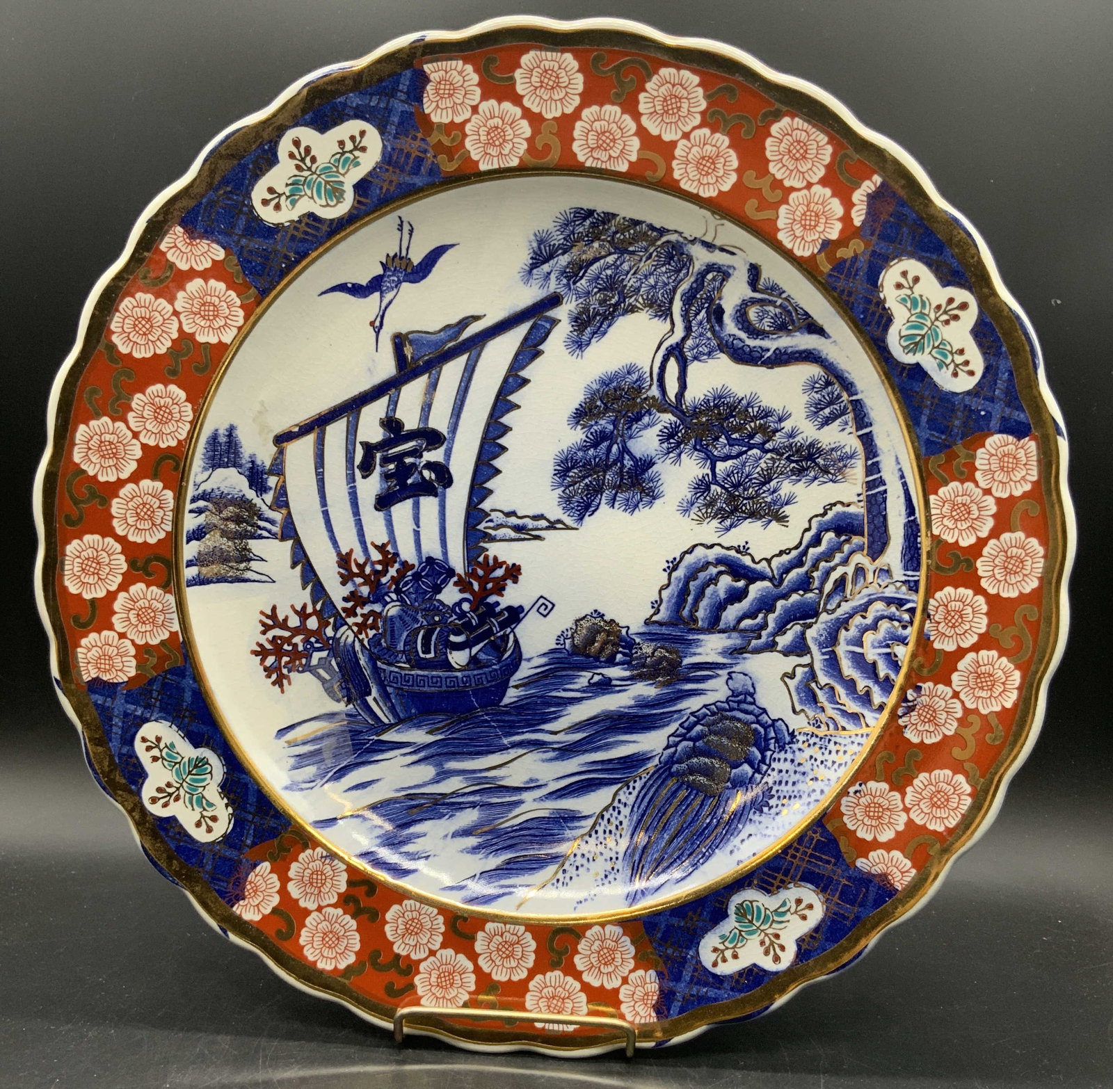 Vintage Asian Imari Porcelain Charger Plate 14in: A vintage Asian Imari porcelain charger plate. Hand painted in cobalt blue, saffron, and gilt. Seaside motif features a ship, crane, and turtle amongst the shore & foliage. Scalloped rim. Underside si