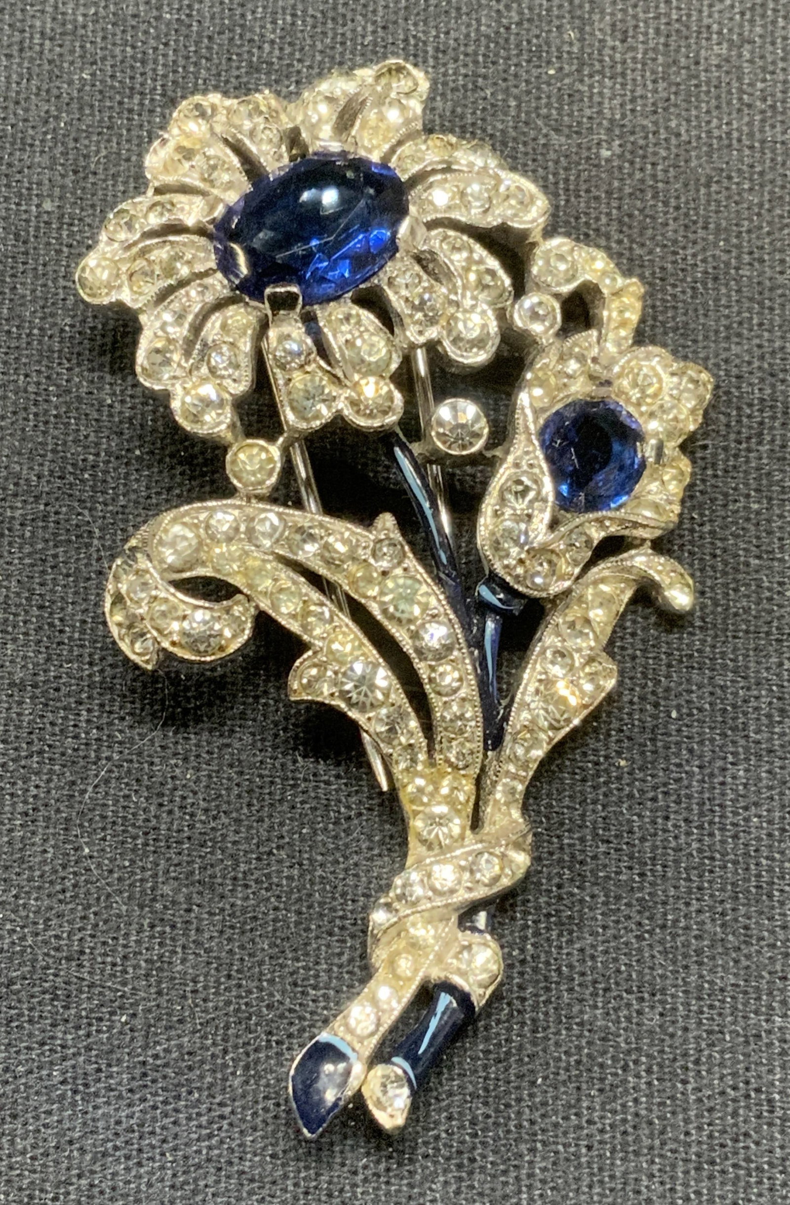 Vintage Trifari Silver Tn Crystal Flower Fur Clip: Vintage Trifari silver tone flower fur clip. Colorless and blue crystal decoration with blue enamel detail. Signed to underside. Measures approx. 2.25 x 1.5 inches. Some scratching observed. Estate je