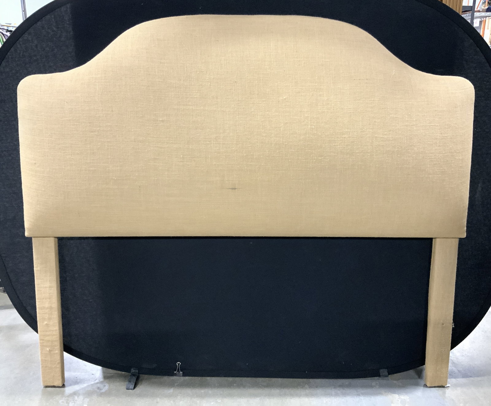 BALLARD DESIGNS Burlap Upholstered Headboard Tan: Tag on backside reads BALLARD DESIGNS. Headboard is upholstered with tan toned burlap. Sides of top curve upwards toward center. Backside is white toned. Headboard has 2 supports. Piece measures appro