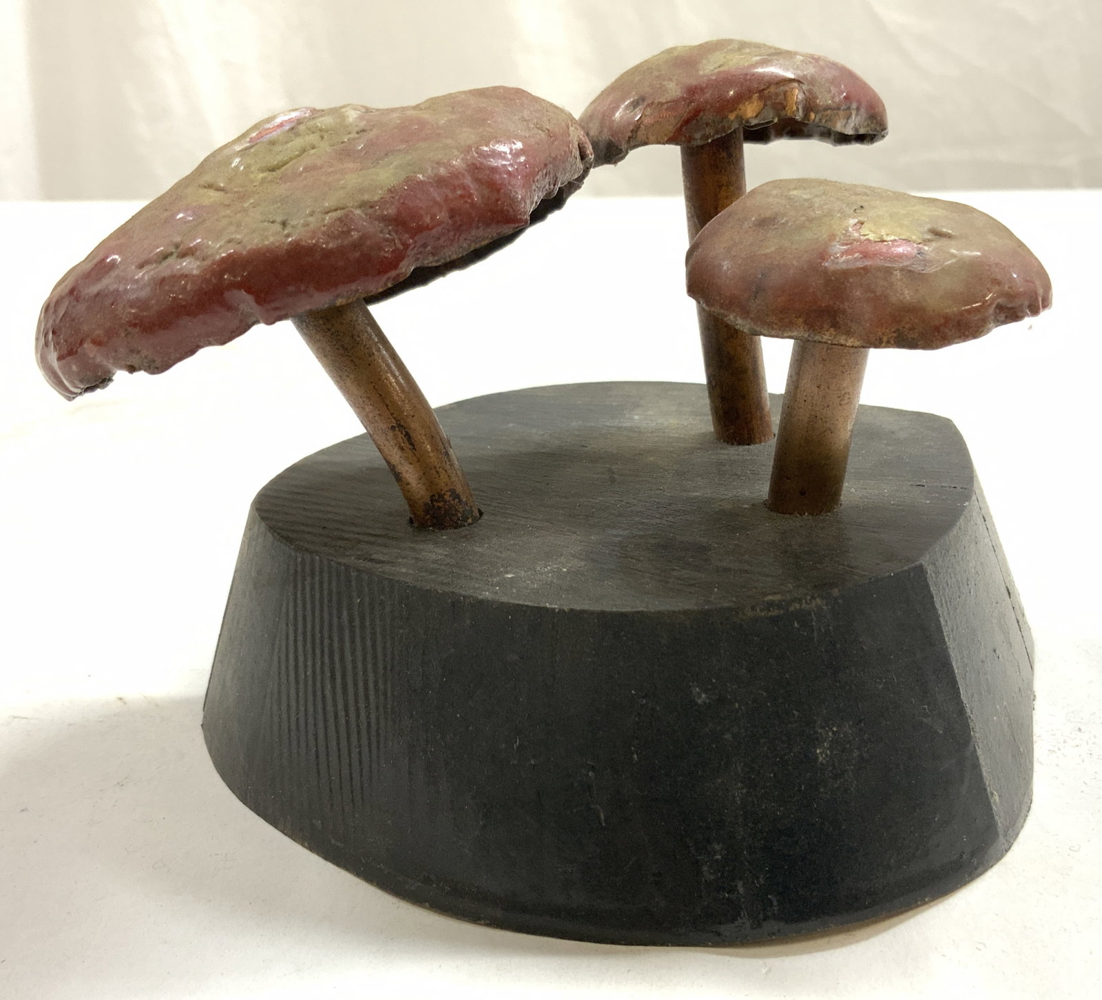 STEFAN B SEGAL Metal & Wooden Mushroom Sculpture: Underside is signed STEFAN B SEGAL. Sculpture is metal with wooden base. Piece has 3 mushroom forms with red, copper & brown tones. Sculpture measures approximately 5.25 inches wide 3.25 inches tall. 