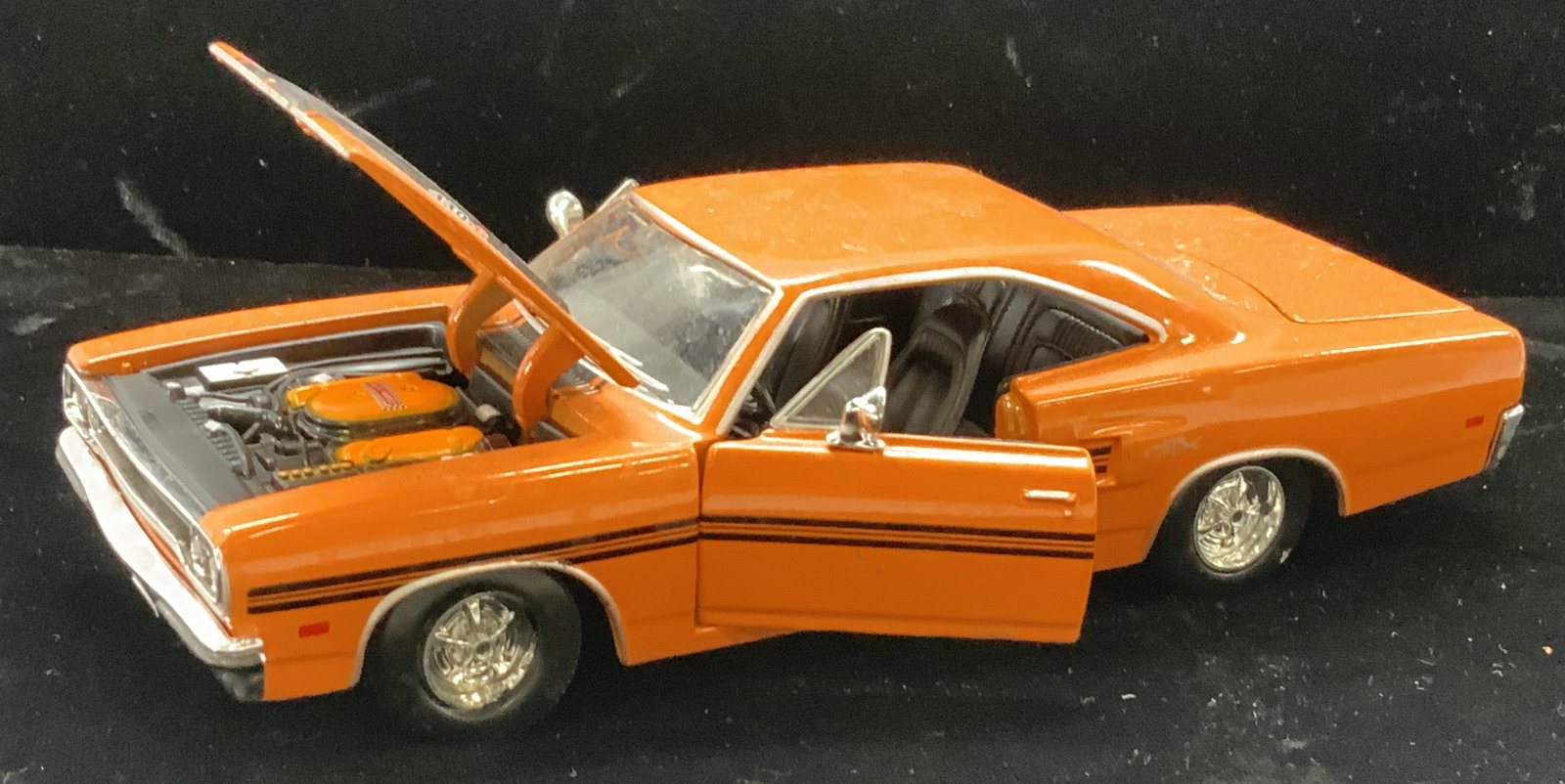 Collectible 70s Plymouth GTX Model Car Maisto 2009: Orange dye cast metal 1970 Plymouth GTX model car, manufactured by Maisto c. 2009 Chrysler Group LLC. Hood and doors open. 1 wheel bent but does not impede wheels from moving (move smoothly , no squea