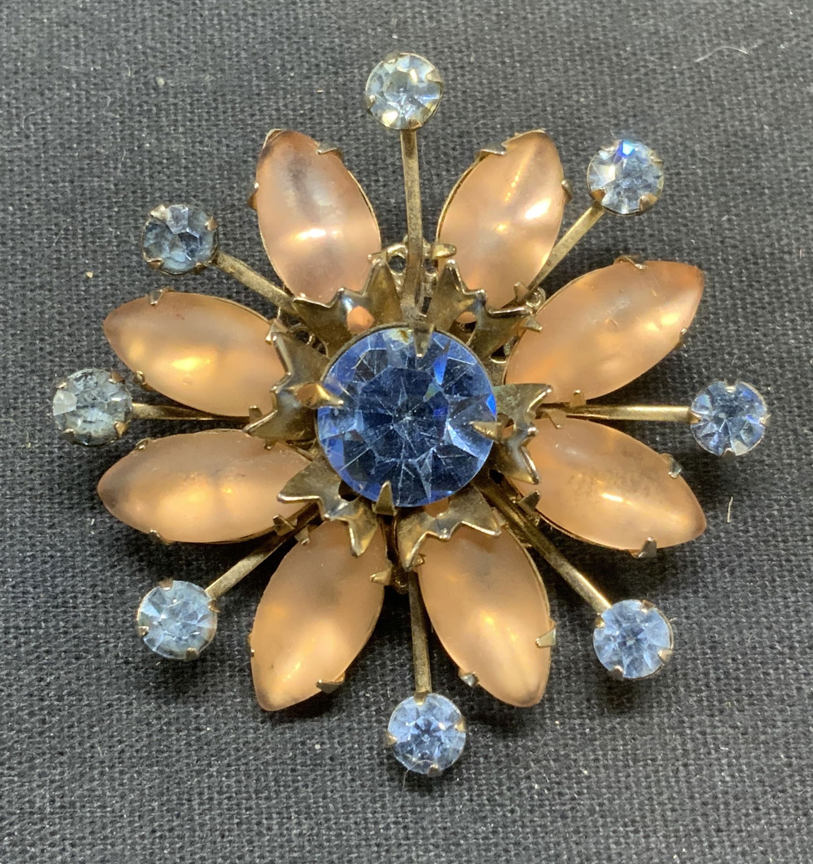 Silver Tone Crystal & Lucite Flower Brooch: Silver tone flower brooch with blue crystal and pink lucite decoration. Hinge pin to underside. Measures approx. 1.75 inches diameter. Some scratching observed. Estate jewelry, costume jewelry, cockta