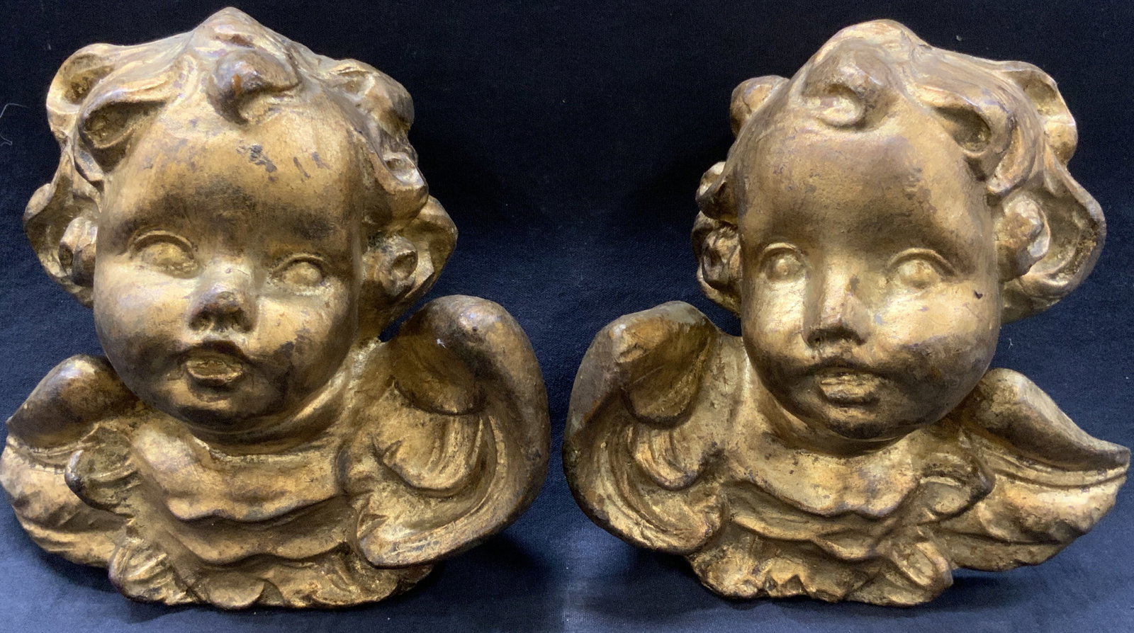 Pr Gold Leafed Carved Wooden Cherub Heads: Pair of gold leafed wooden cherub heads with wings. Approx 8 inches tall and 8.5 inches wide. Moderate wearing to gold leaf to figures and evident scratches observed. Gilt wooden cherub heads, cherub 