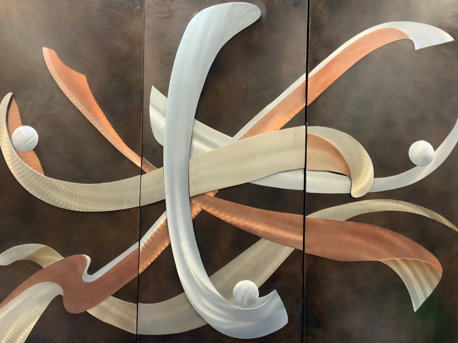 Three Panel Brushed Metal Modern Art: Modern art tri panel / triptych piece with brushed metal in tones of silver and copper with raised warping forms. No frames. Approx 42 inches tall and 17.5 inches wide. Moderate scratches to metal in 
