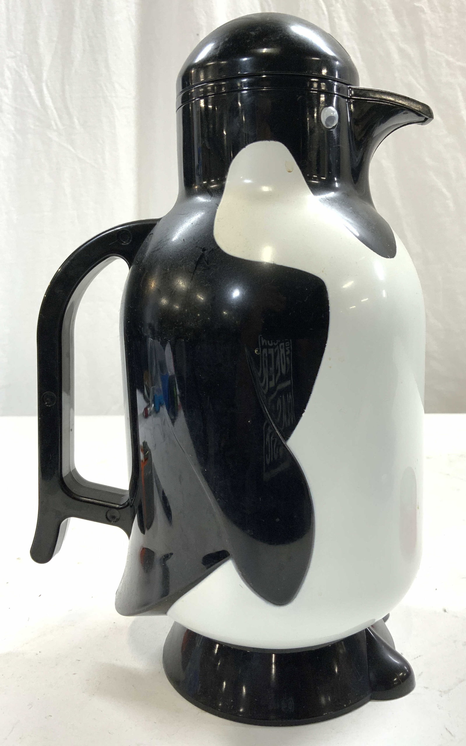 METROKANE Lidded Penguin Teapot Coffee Pot Carafe: Underside of piece reads METROKANE. Piece depicts a penguin. Teapot is plastic. Piece includes lid. Teapot is footed. Measures approx 11 inches tall 7 inches deep 5 inches wide. Carafe Teapot, coffee 