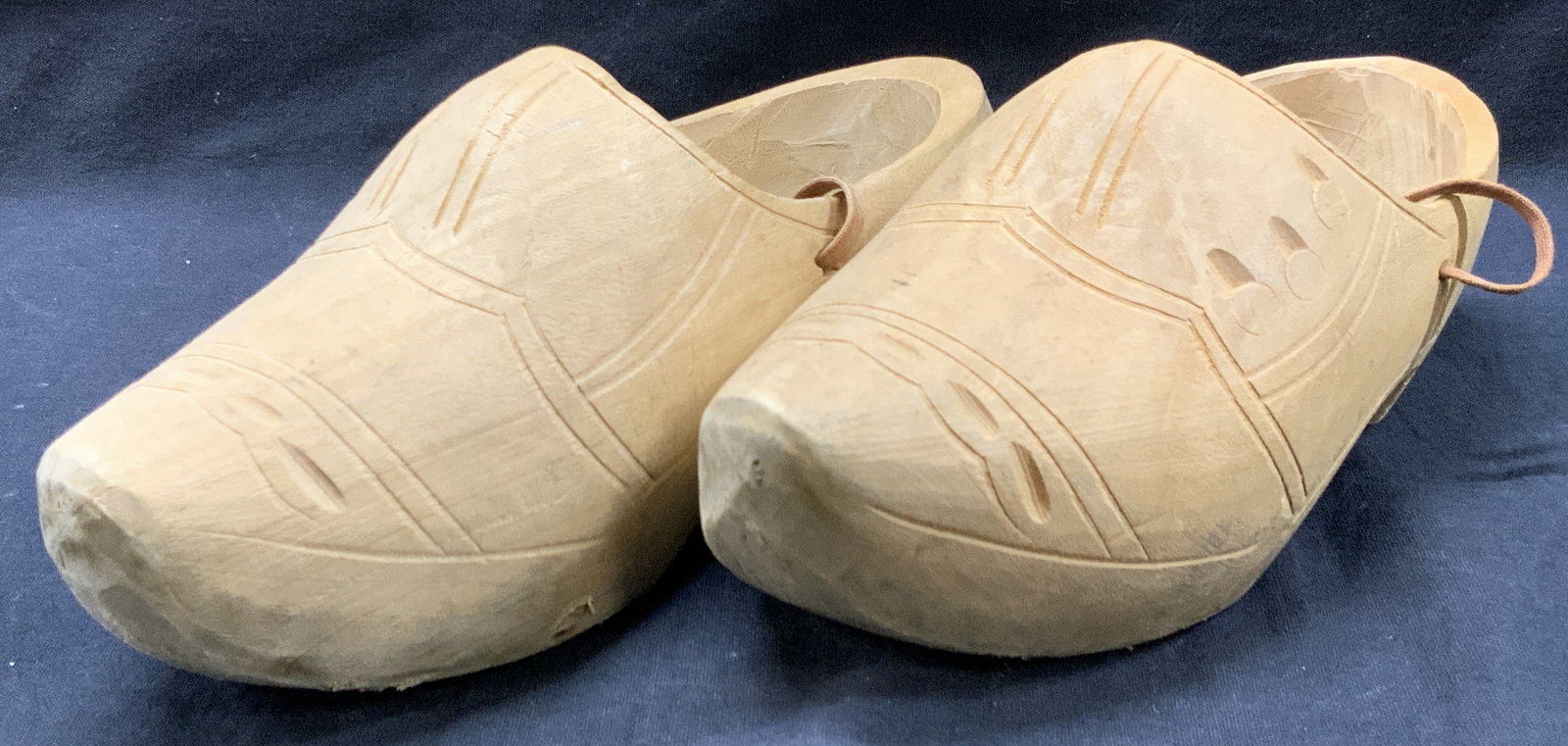 Pr Artisan Carved Wooden Clogs: Signed on underside with names. Carved clogs with etched detailing of buckles and laces. Approx 9 inches long and 3 inches wide. Moderate wearing and blemishes to wood due to age and use. Carve wooden